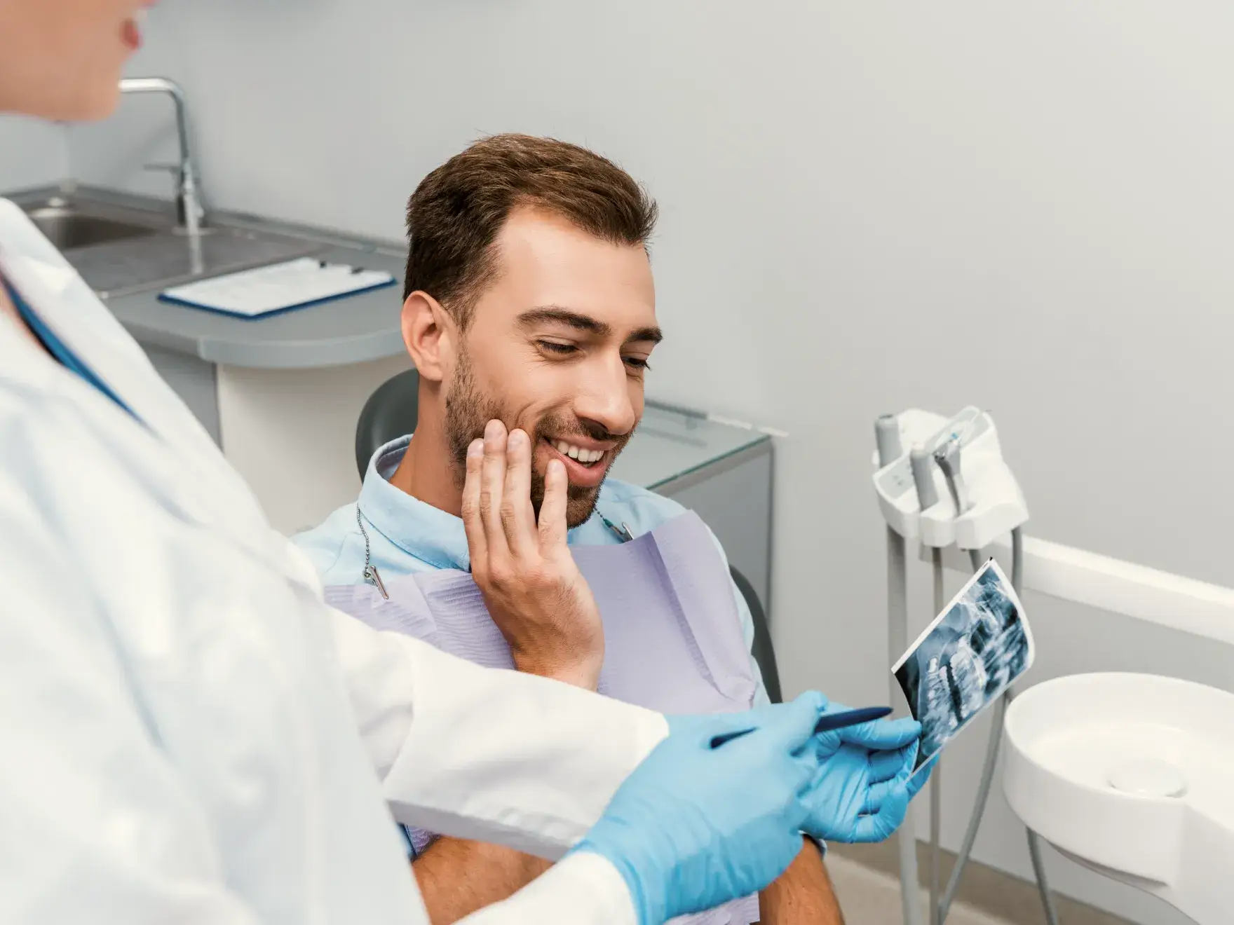 A man in a dentist's chair holding a picture of a patient.