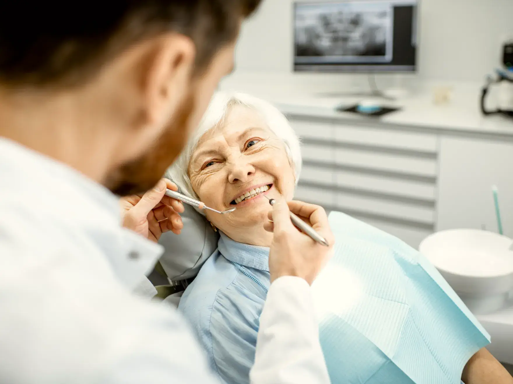 A woman sitting in a dentist chair with a toothbrush in her mouth.