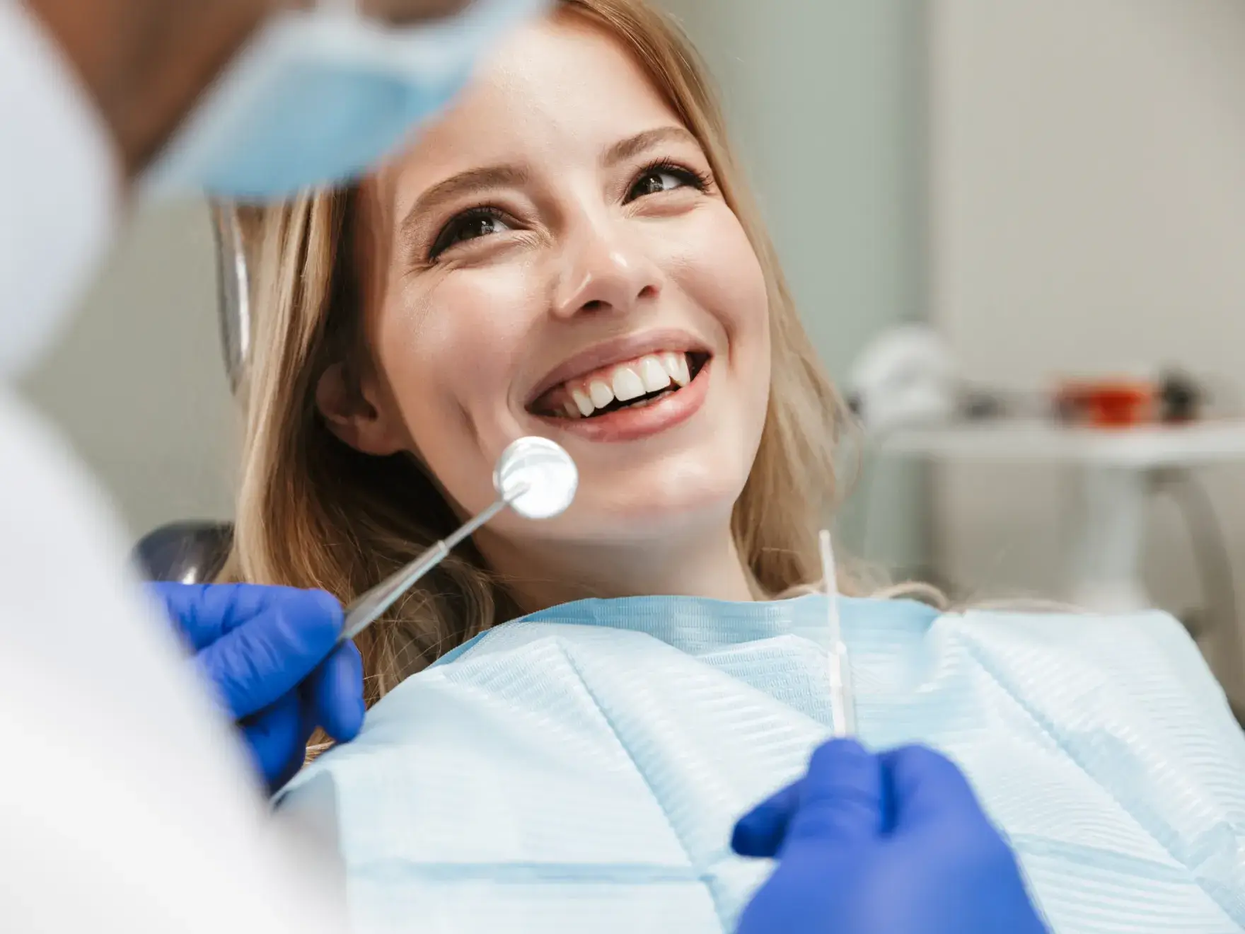 A smiling woman getting her teeth checked by a dentist.