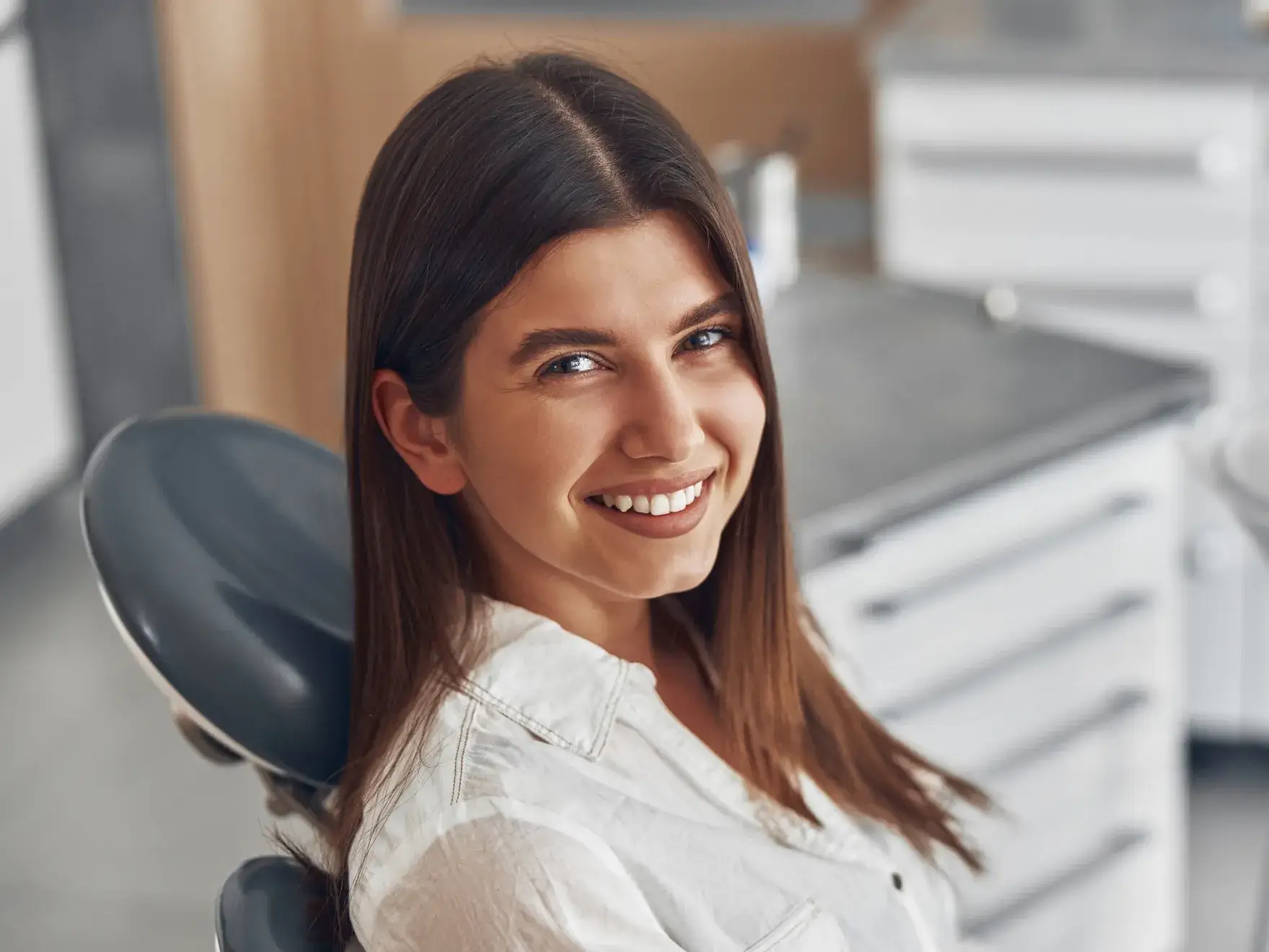 A woman sitting in a dentist chair smiling.