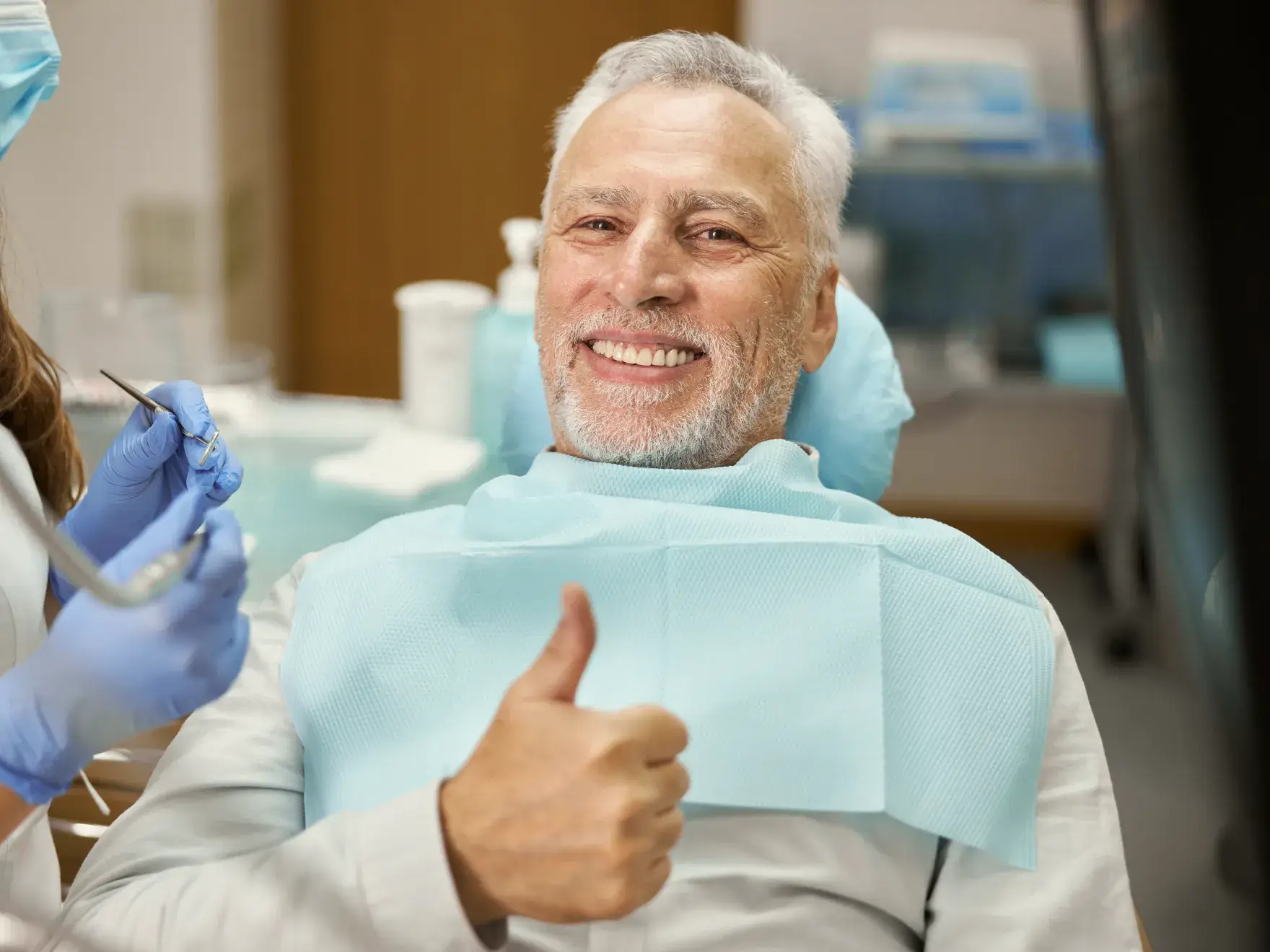 A man sitting in a dentist chair giving a thumbs up.