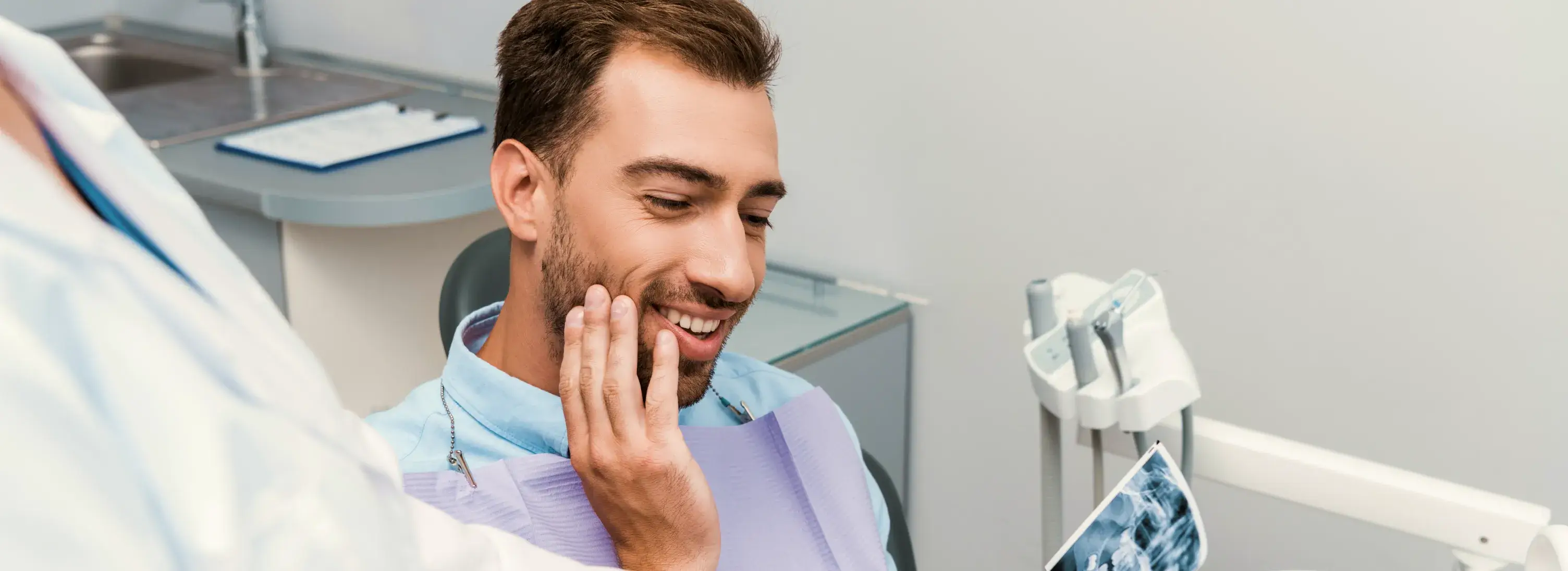 A smiling man in a dental chair with a toothbrush in his hand.