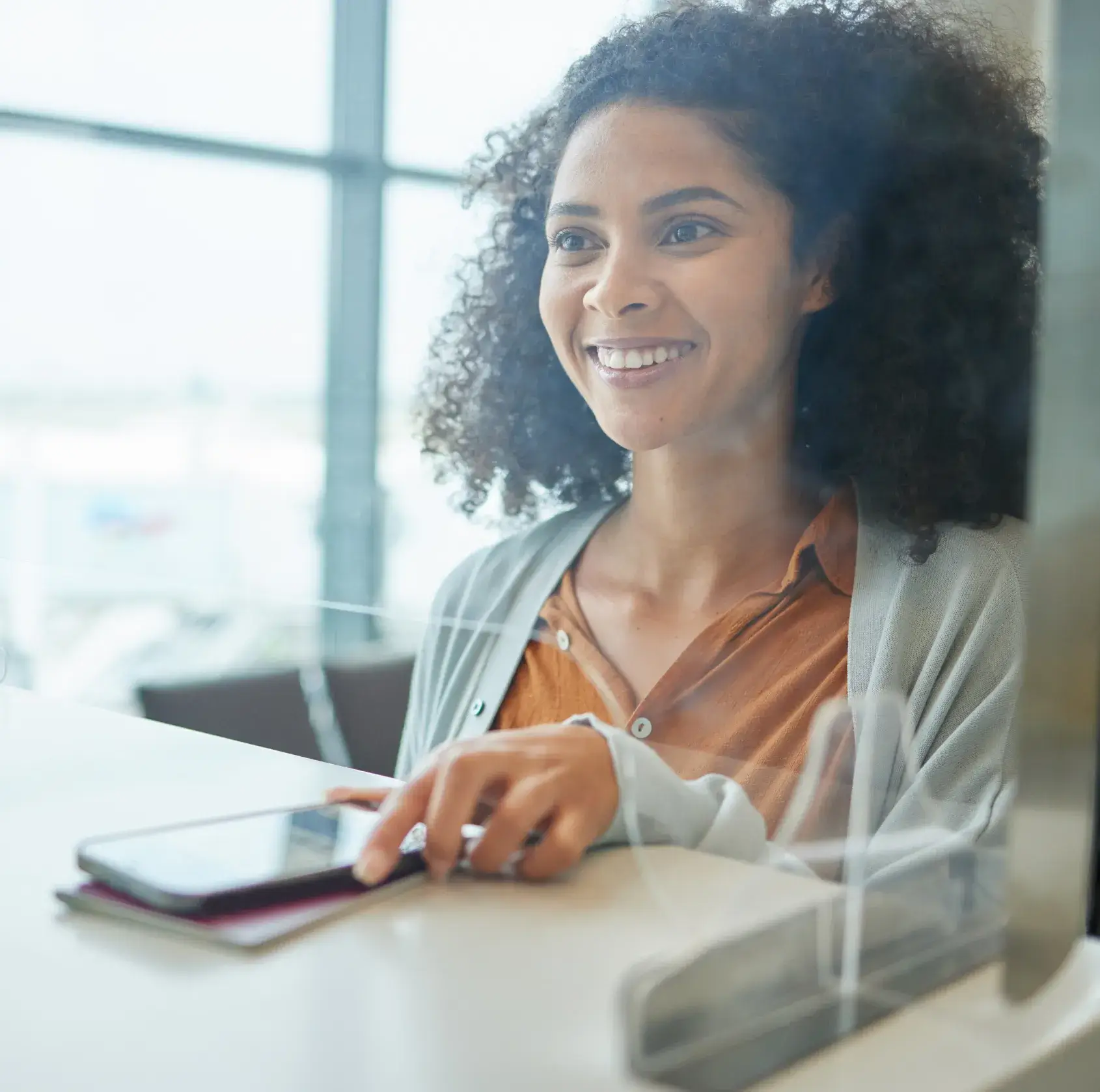 A woman sitting at a table with a cell phone.