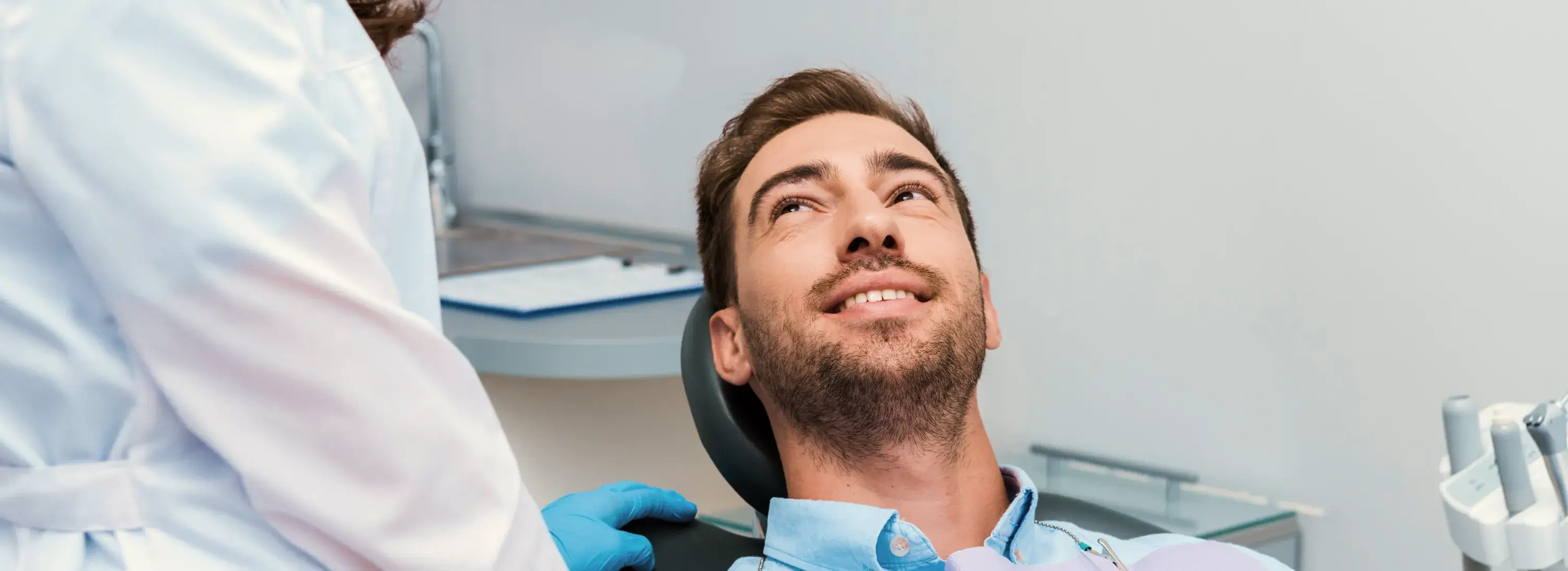 A man sitting in a dentist chair looking up.