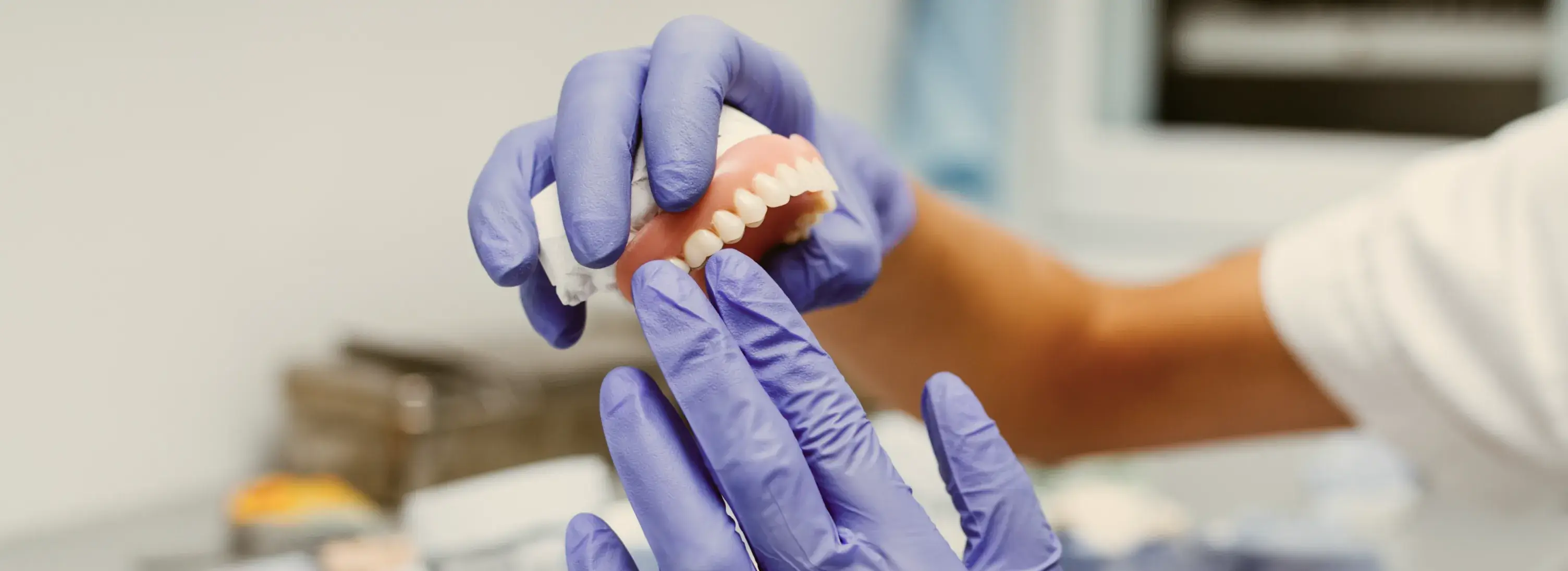 A person in purple gloves holding a toothbrush.