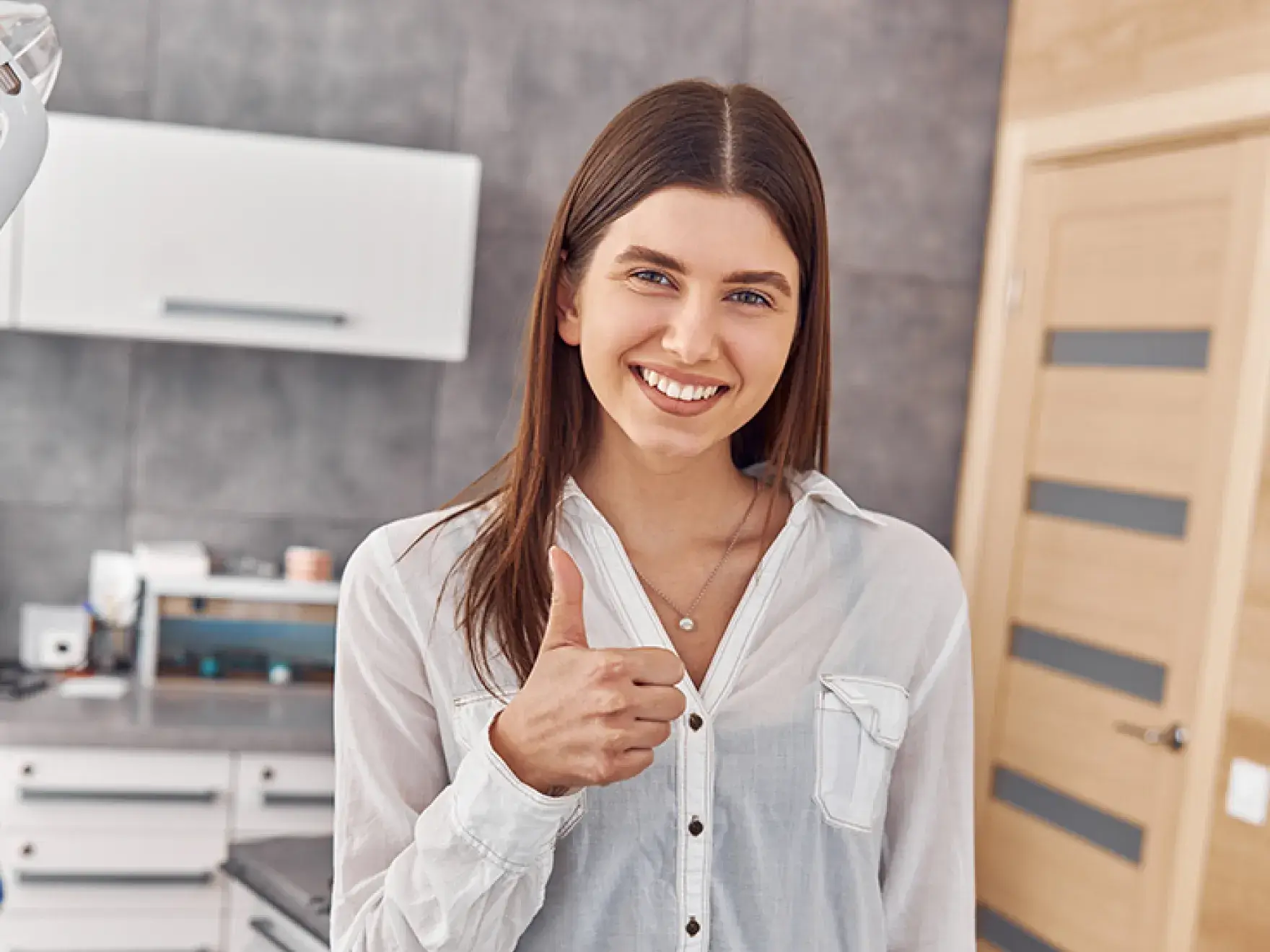 A woman giving a thumbs up in a kitchen.