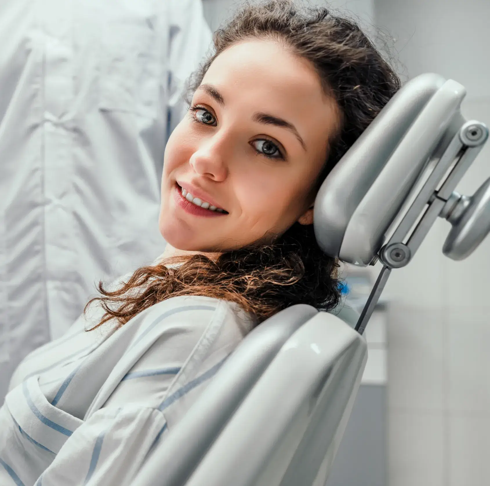 A woman sitting in a dental chair smiling.