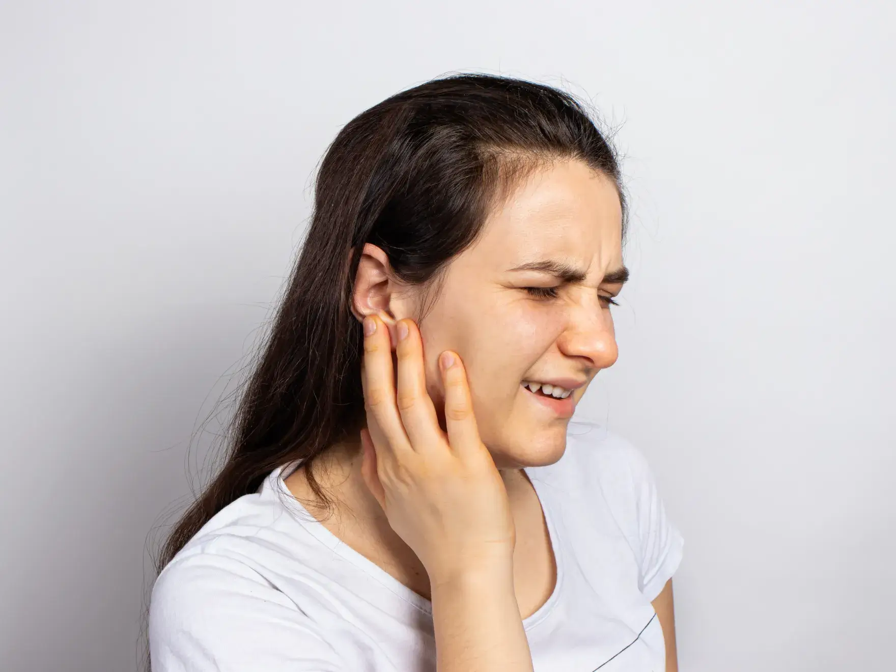 A woman holding her ear to her ear.