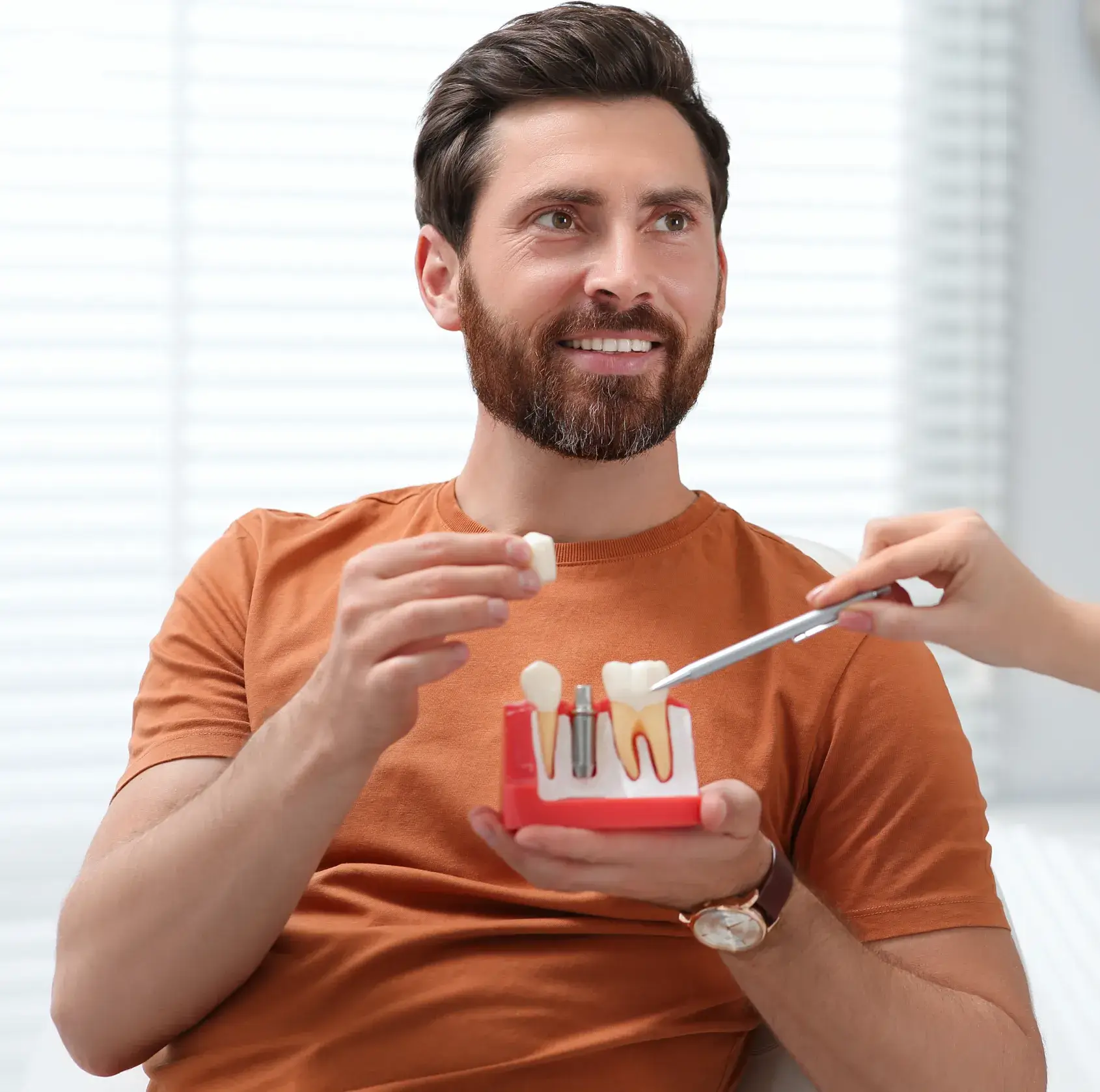 A man holding a toothbrush and a model of a tooth.