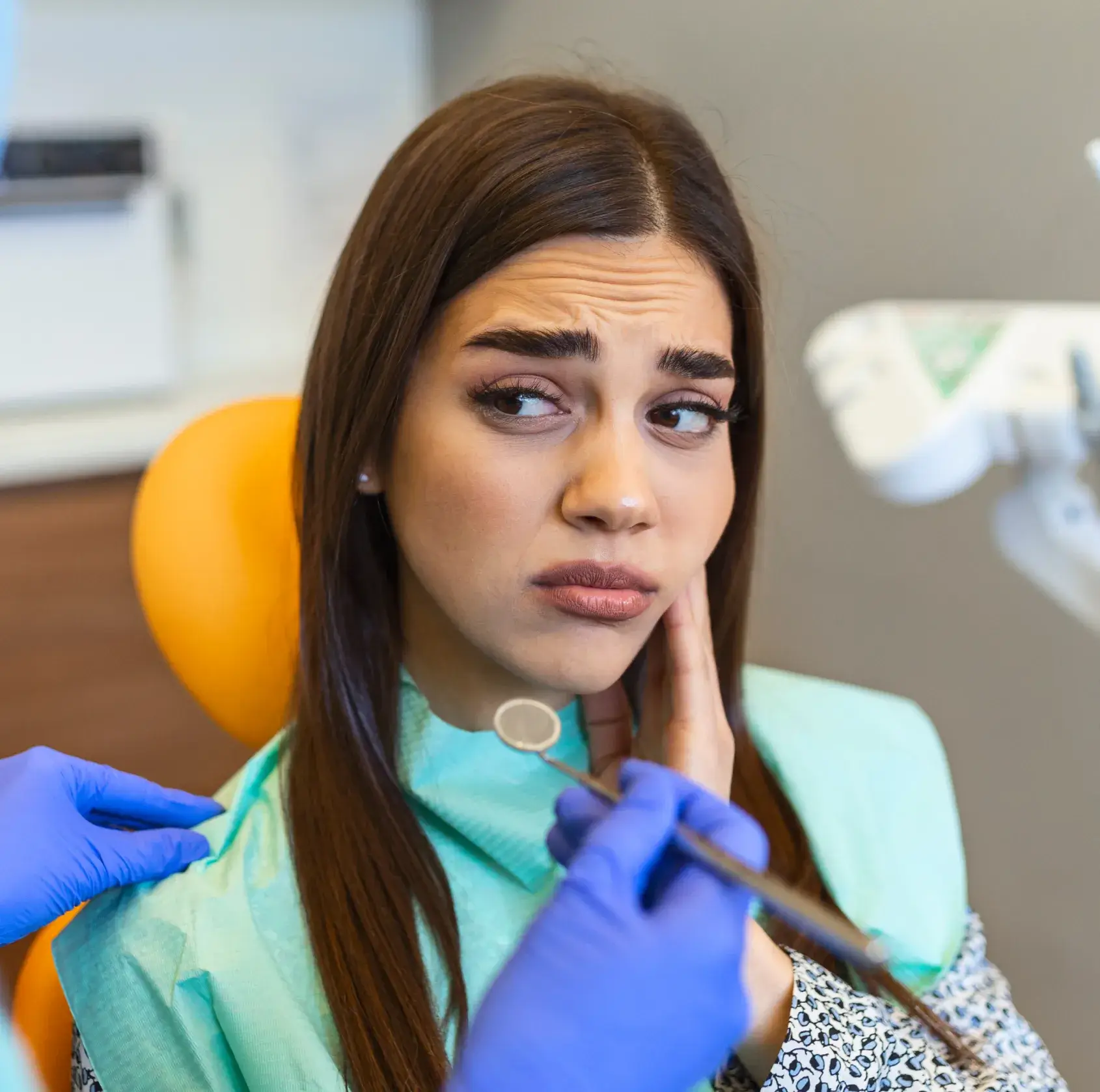 A woman sitting in a dentist chair while holding a pair of scissors.