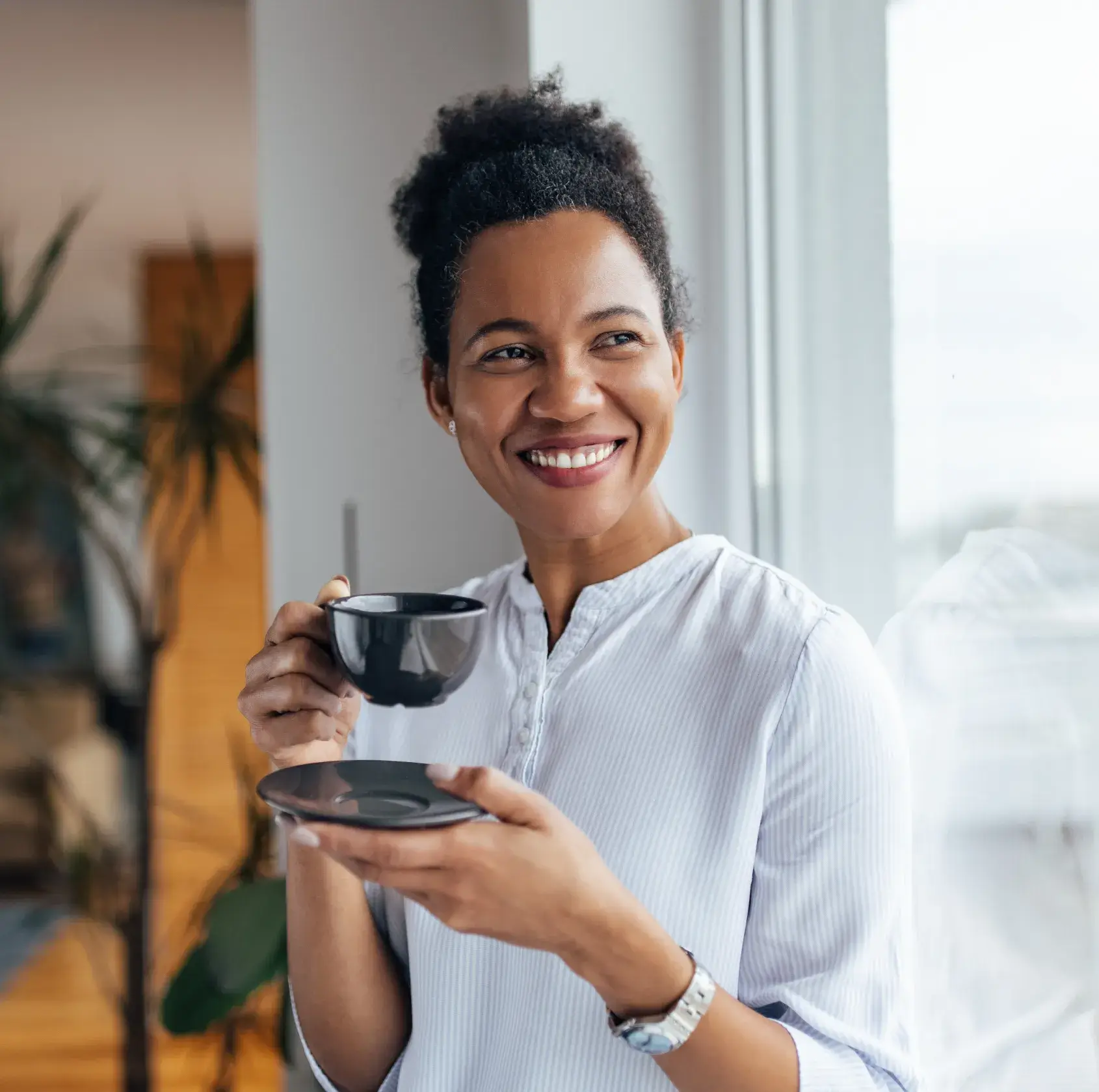 A woman holding a cup of coffee and a plate.