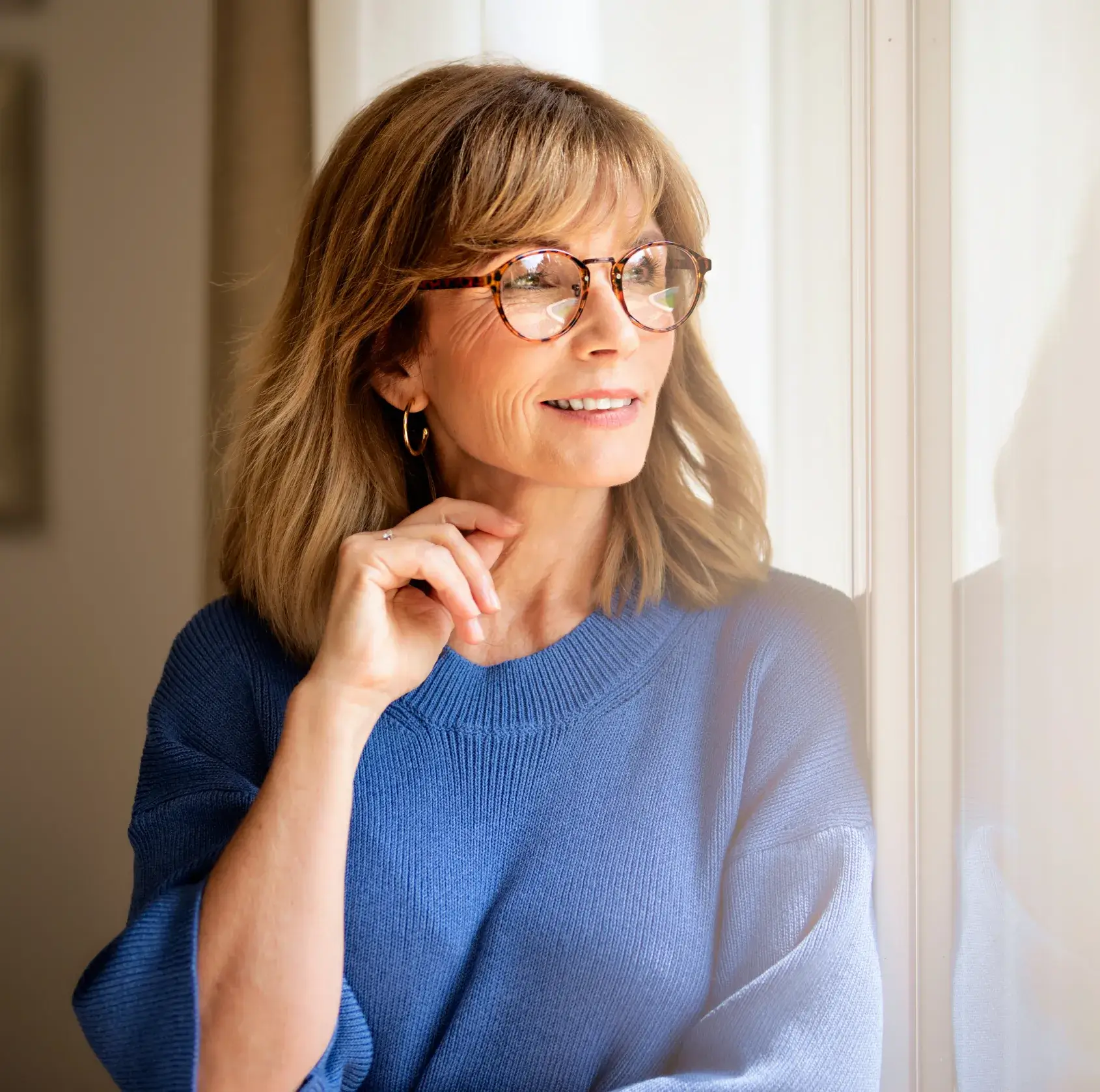 A woman wearing glasses and a blue sweater.