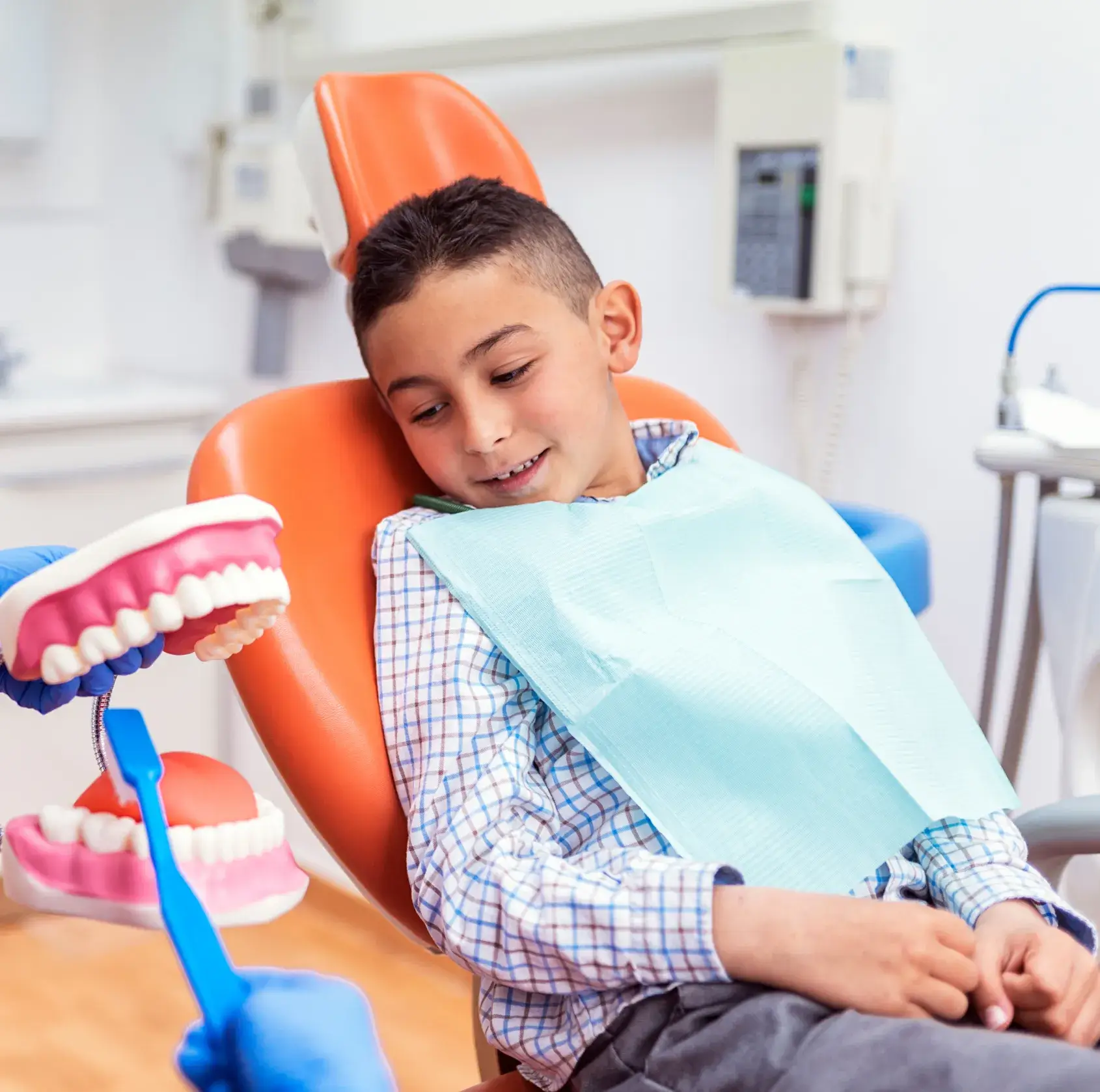A young boy sitting in a chair with a toothbrush.