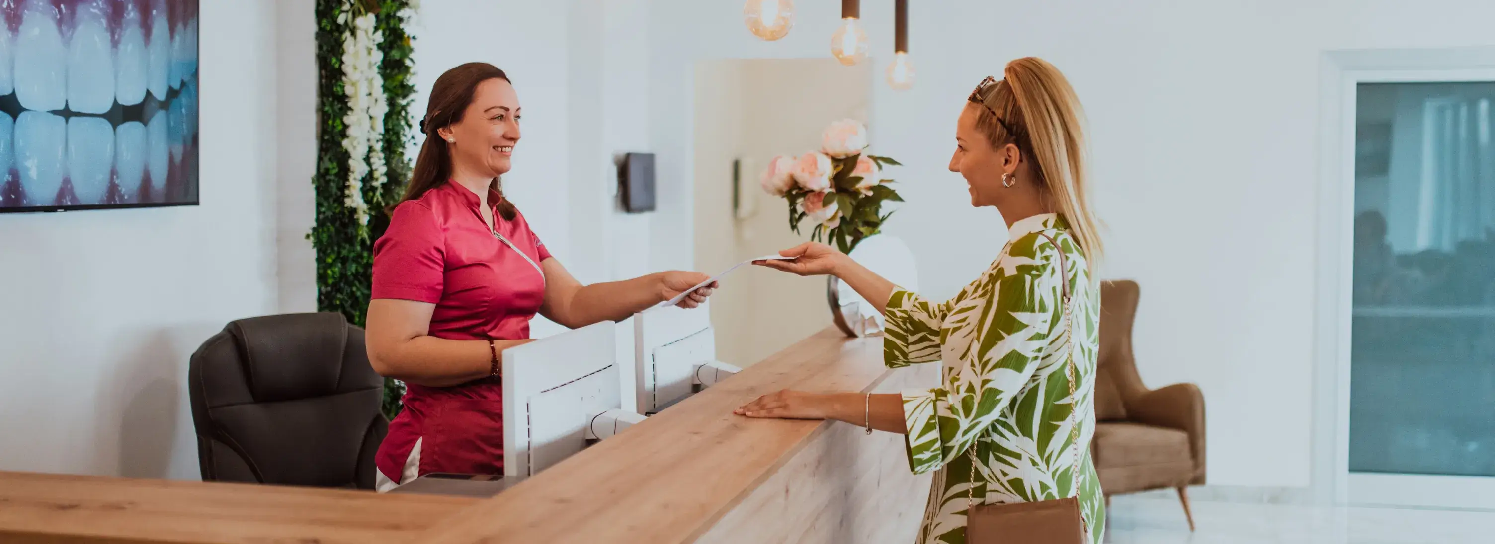 Two women standing at the front desk of a dental office.