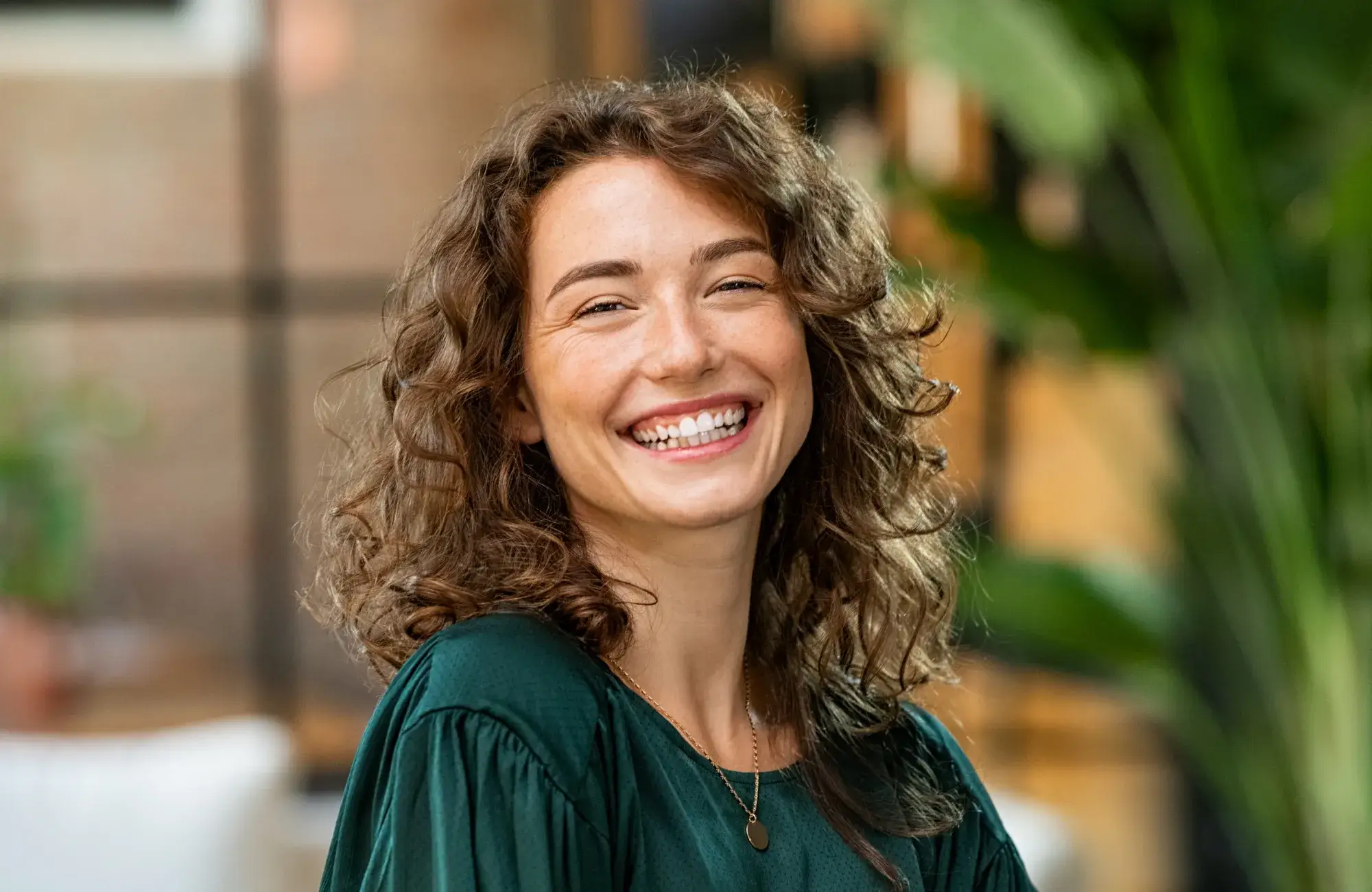 A woman with curly hair smiling at the camera.
