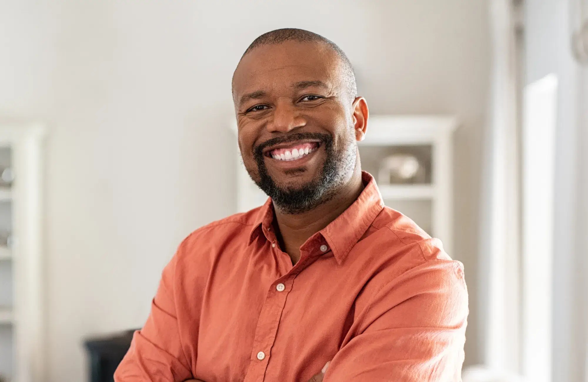 A man in an orange shirt is smiling.