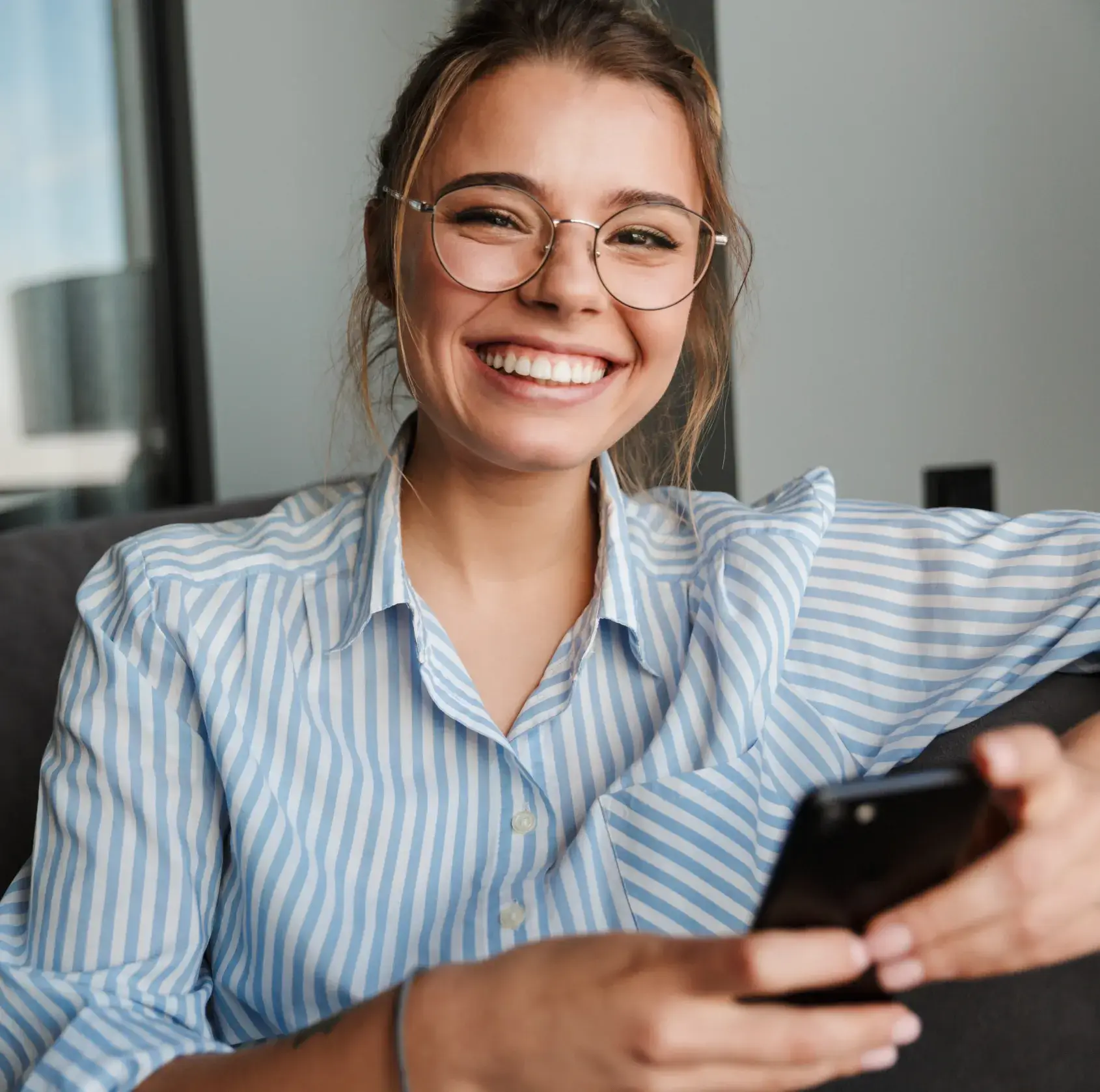 A woman wearing glasses is looking at her cell phone.