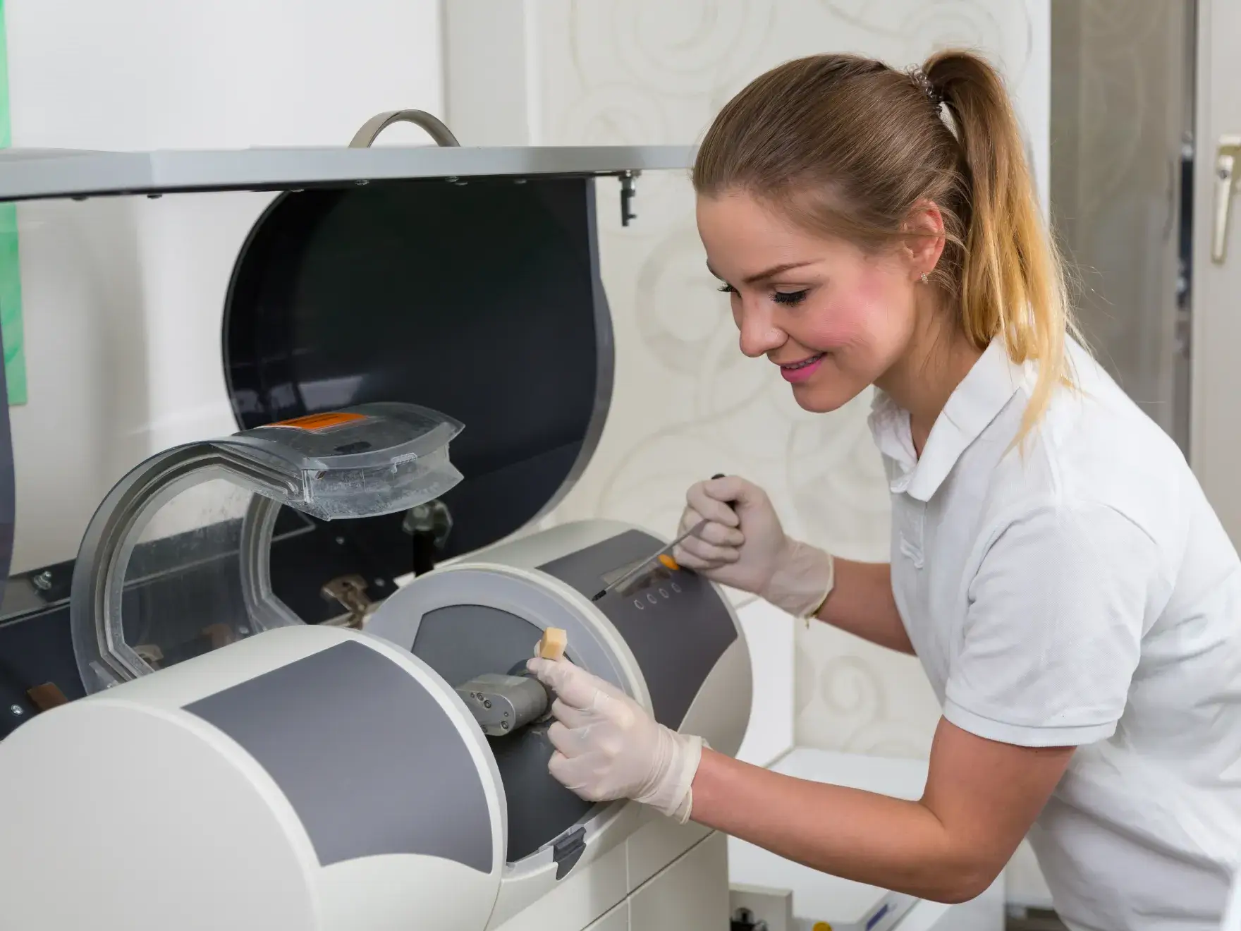 A woman in white shirt and gloves working on a machine.