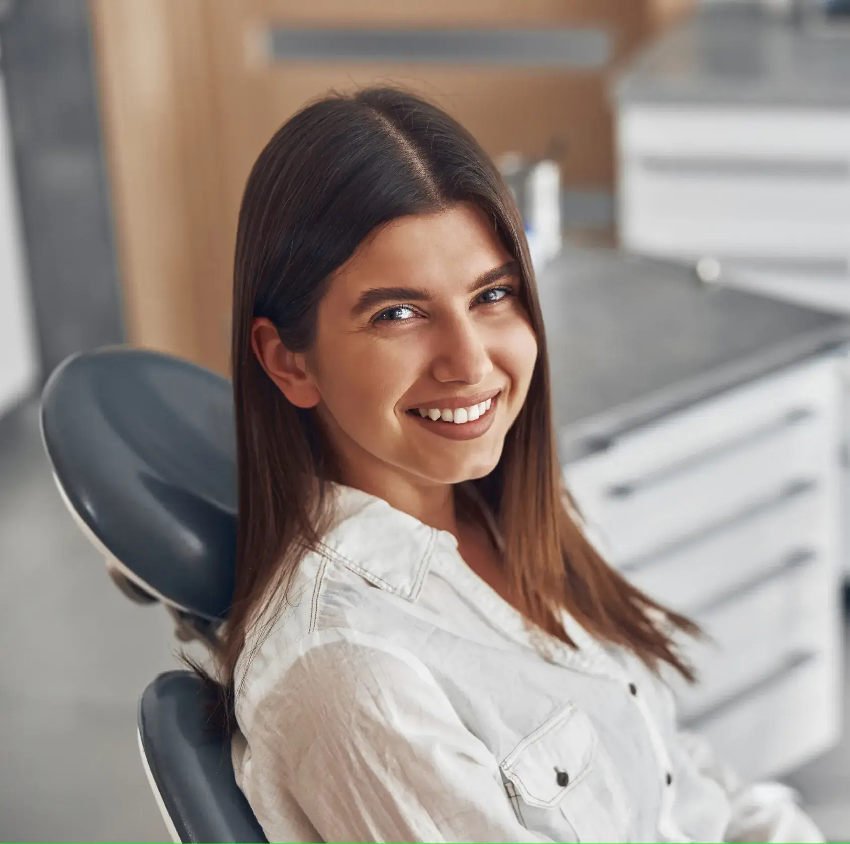 A woman sitting in a dental chair smiling.