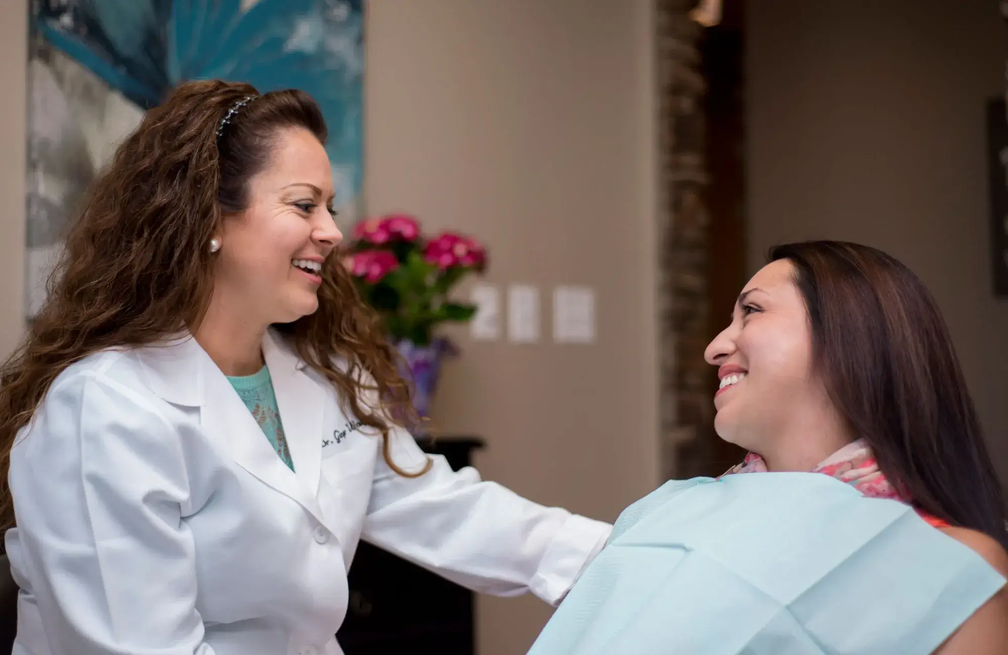 A woman getting her hair done by a woman in a white coat.