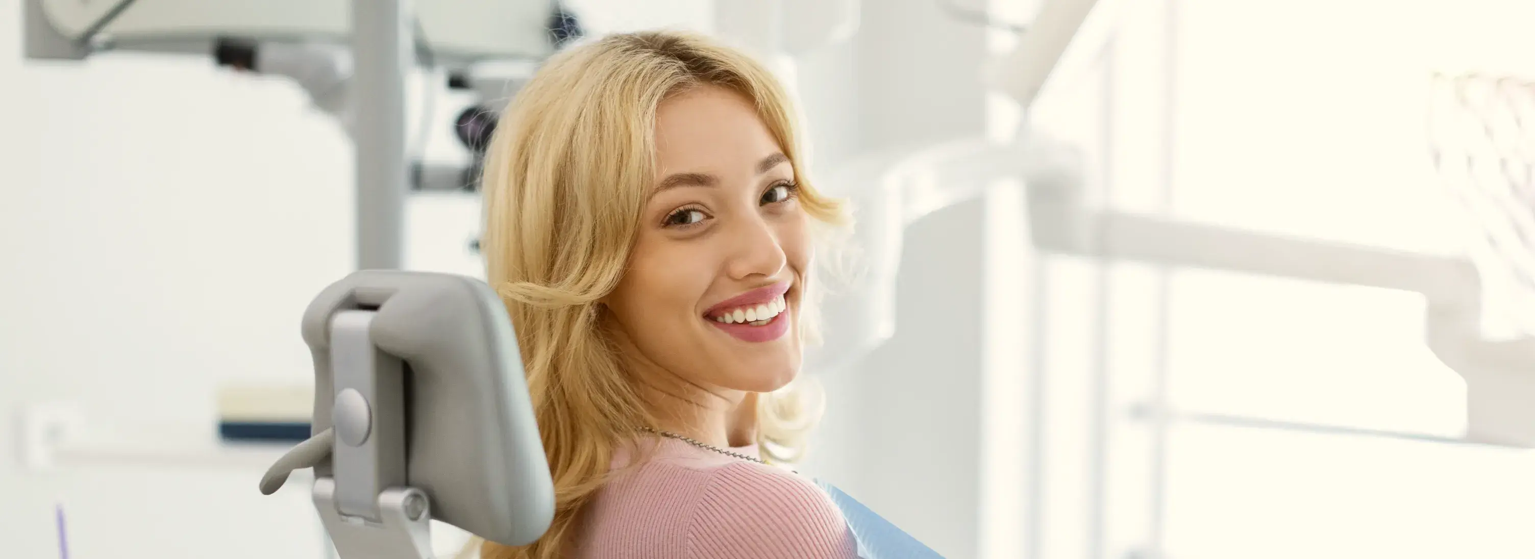 A woman in a dentist chair smiling at the camera.