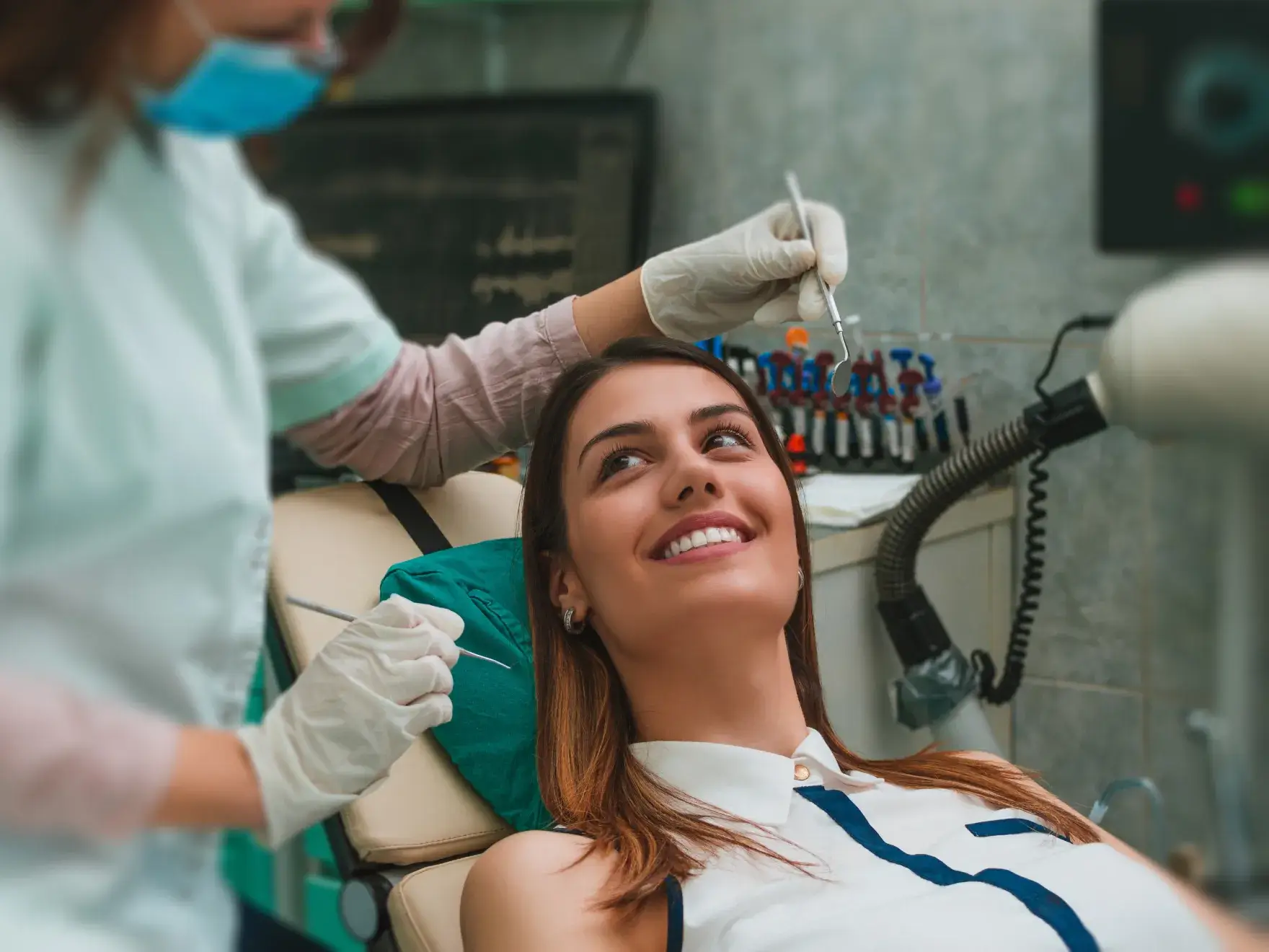 A woman sitting in a dentist chair getting her teeth brushed.