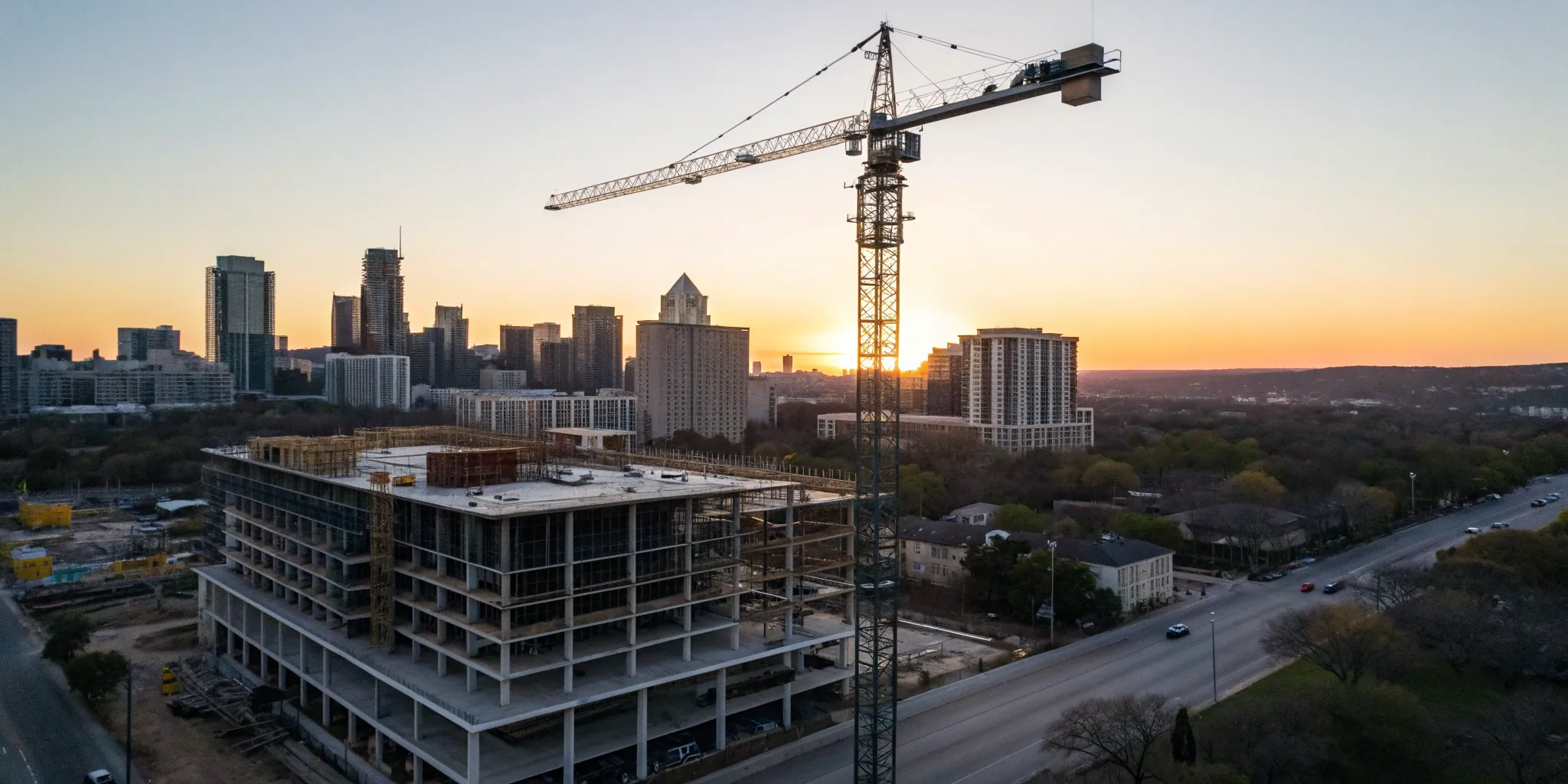 An Austin construction company project with a crane and the city skyline at sunset.
