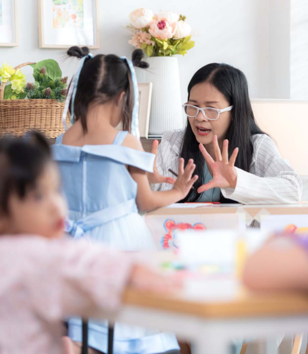A therapist and a young girl in a classroom room with toys and educational materials