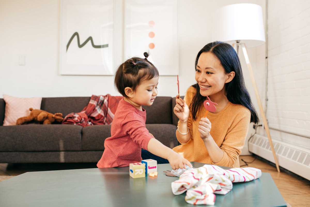 Parent sitting with a toddler while observing early developmental behaviors associated with autism, including limited eye contact, repetitive play, and sensory sensitivity in a calm home setting.