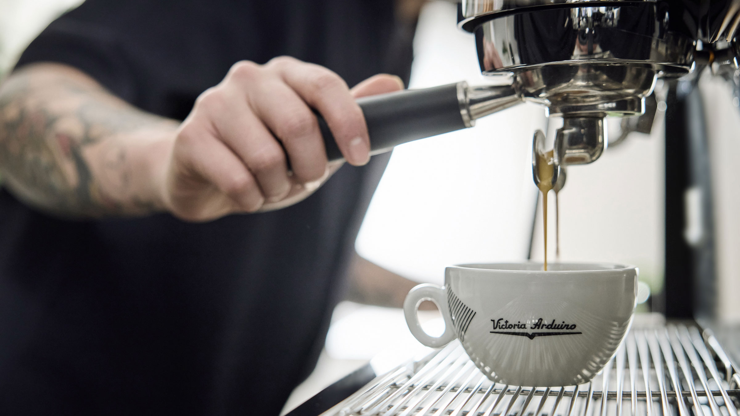 Mikael Jasons arm holding coffee portafilter while it makes coffee