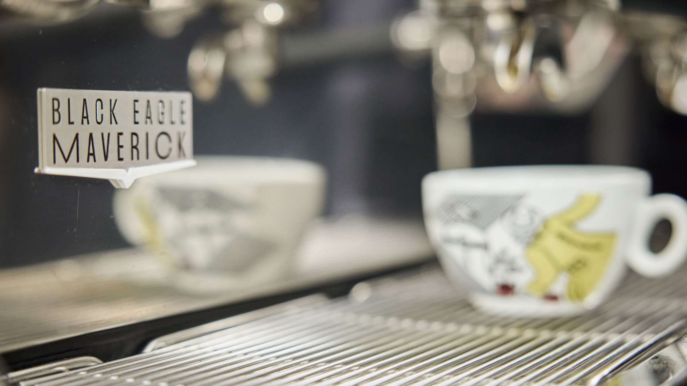 Black Eagle Core coffee machine badge with blurred coffee cup