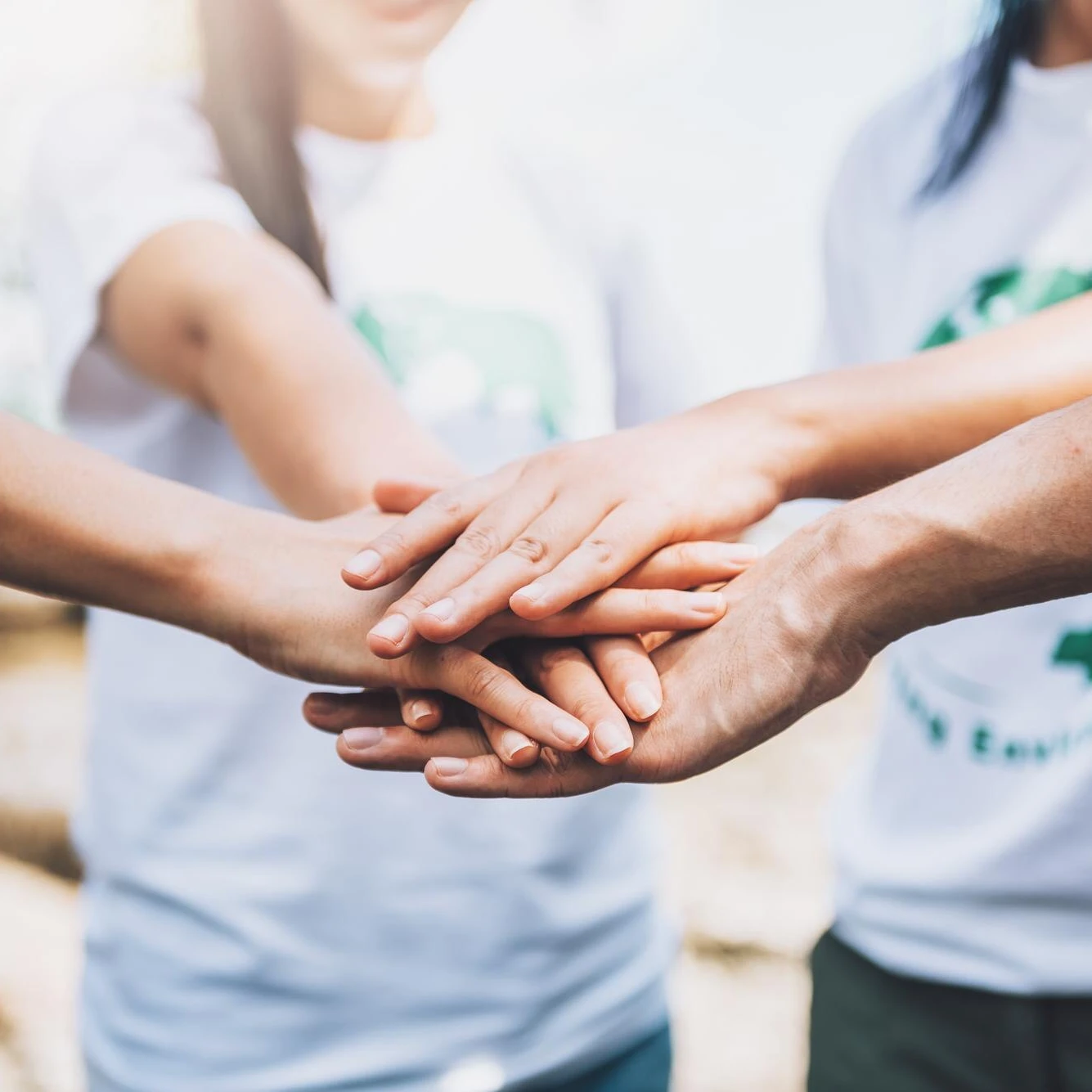 Group of people placing their hands together in a team gesture.