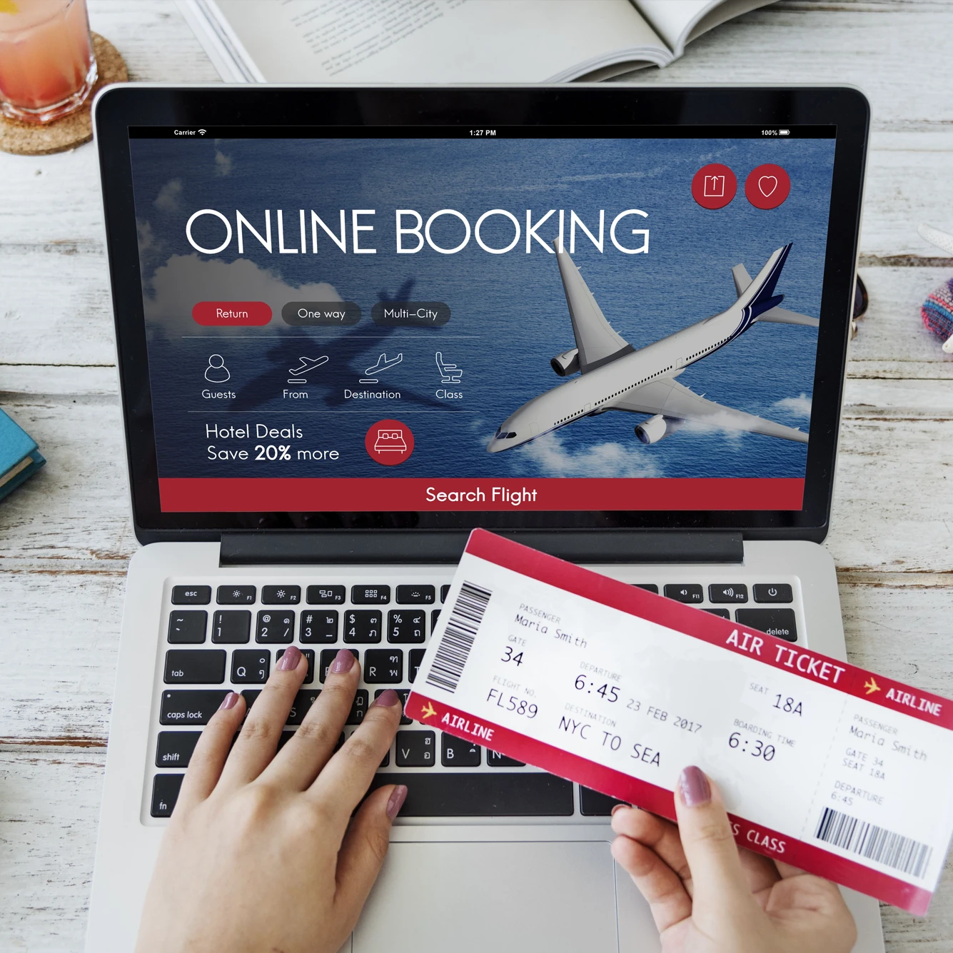 Person booking a flight online on a laptop while holding an airline ticket.