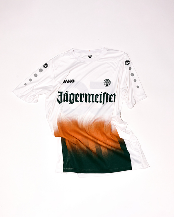 White sports jersey with JAKO logo, Jägermeister sponsor text, and a gradient design in orange and dark green on the lower half.