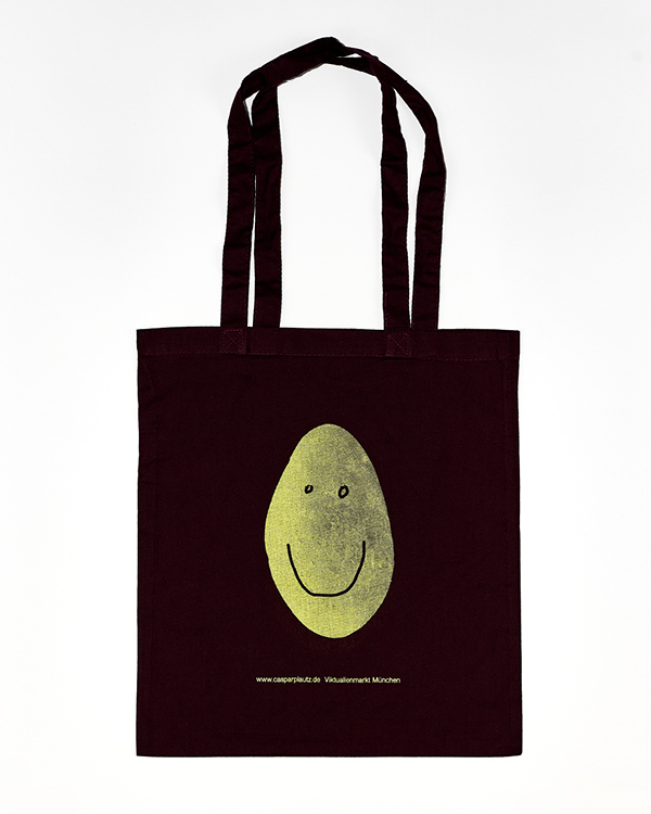 Black tote bag with a yellow smiling face graphic in the center and small white text beneath it.