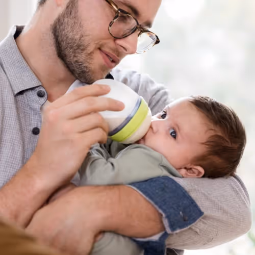 A father feeding his baby a bottle of infant formula