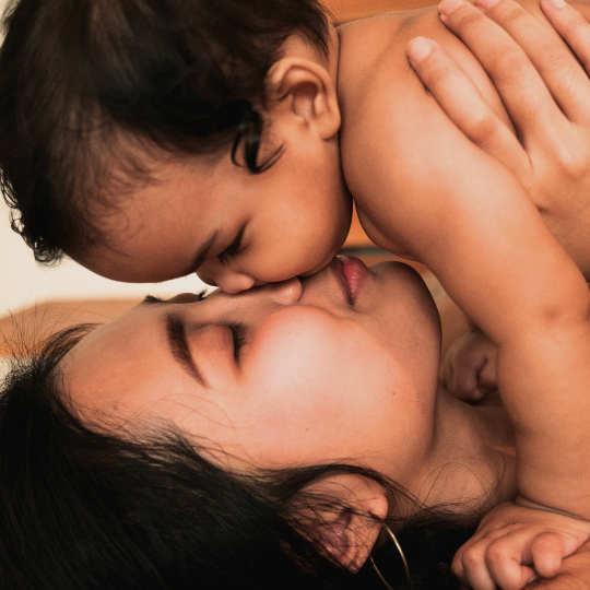 A close-up of a mother and baby's face, bonding and snuggling in a loving embrace.
