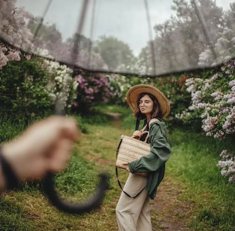 A hand holding an umbrella with a woman standing in the middle
