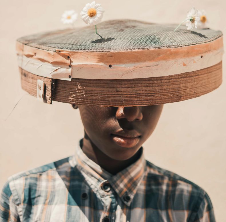 Man wearing checked shirt with rounded hat with petals on top