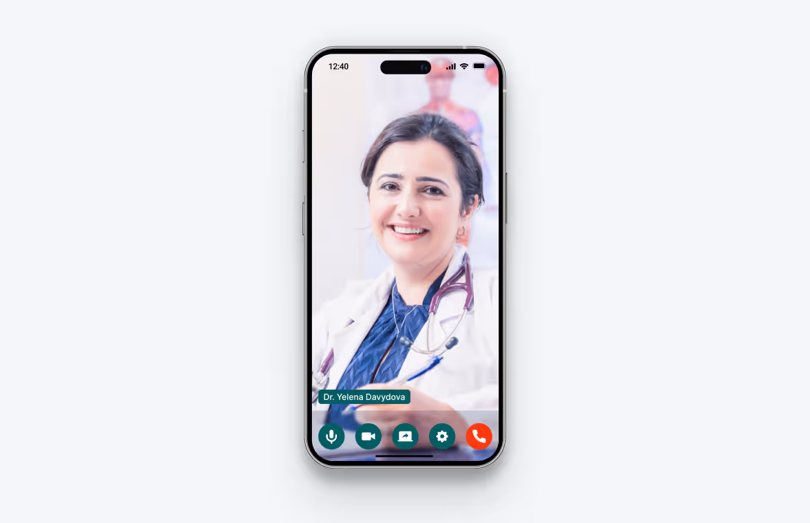 Smartphone screen showing a video call with a smiling female doctor wearing a white coat and stethoscope.