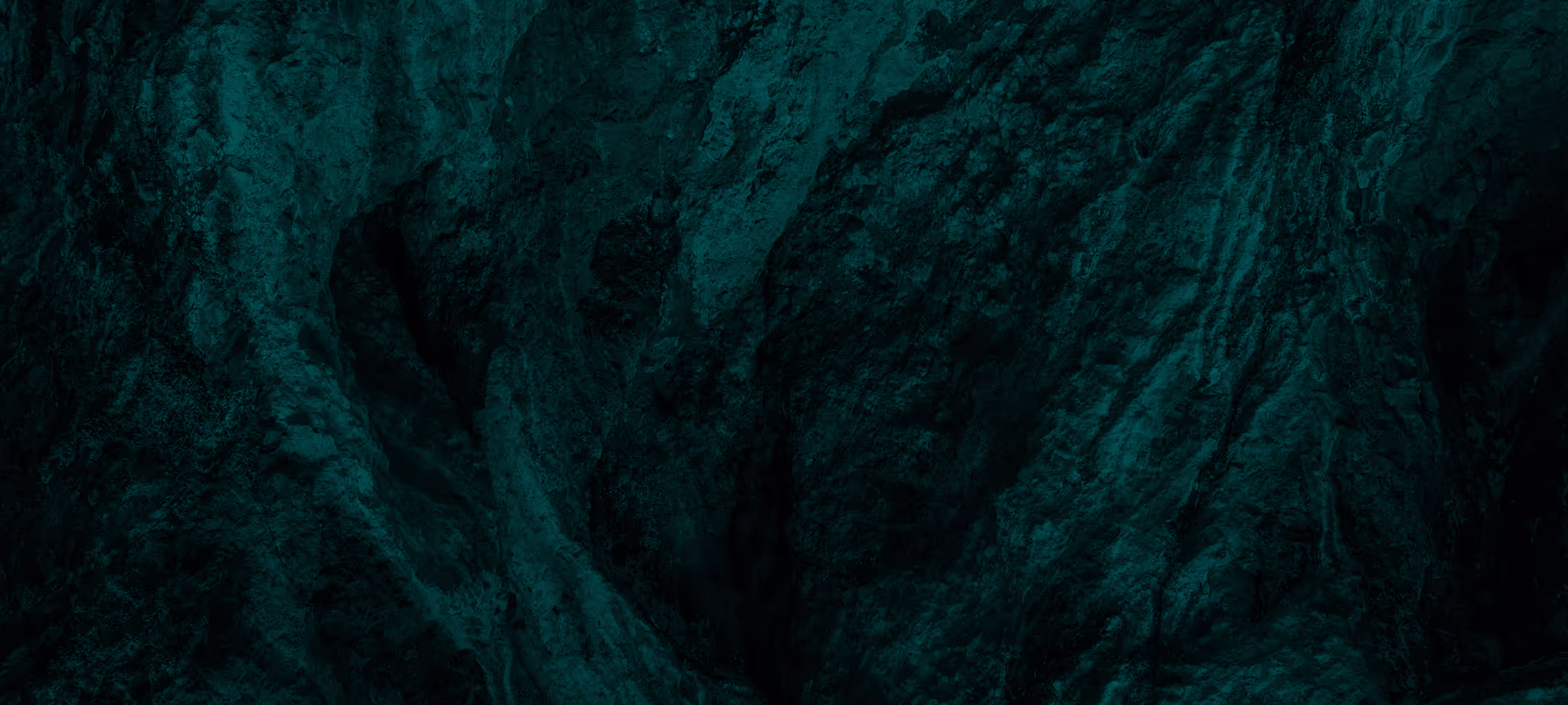 Close-up texture of dark green rough rock surface with crevices.