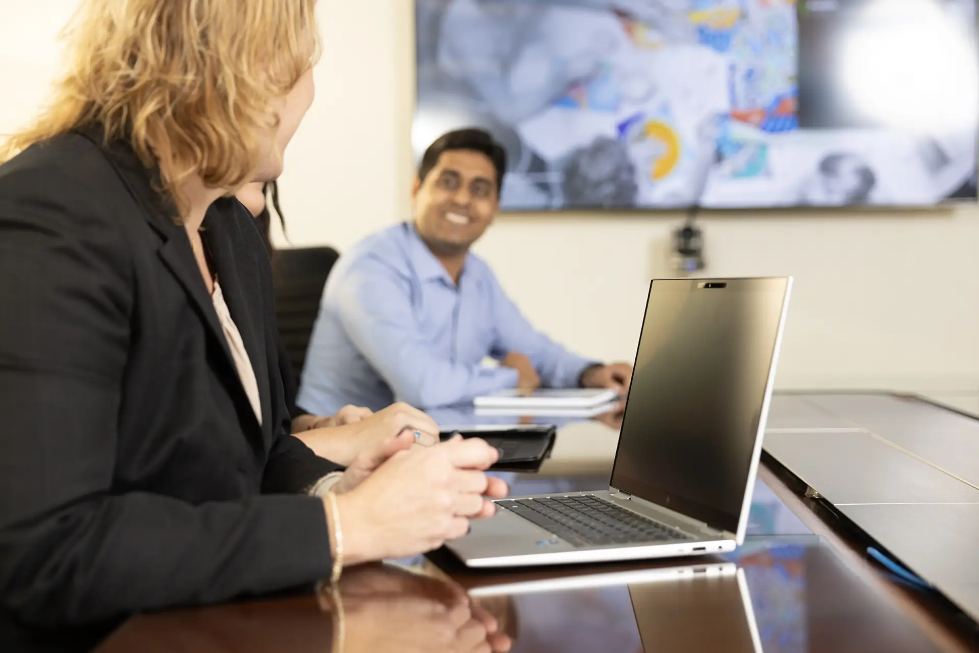 A man and women on laptops in a conference room.