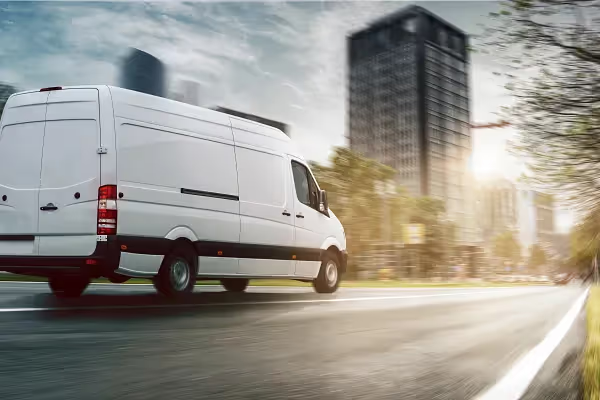 Large white van driving on road.