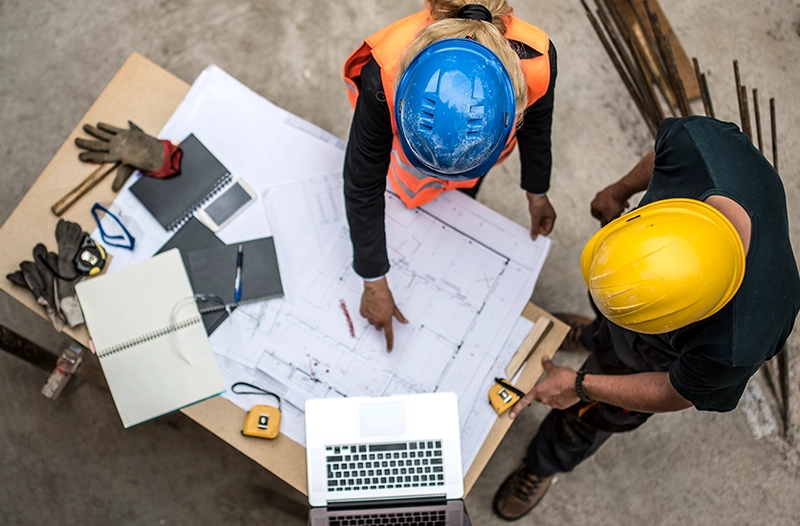 Overhead shot of 2 contractors looking at blueprints.
