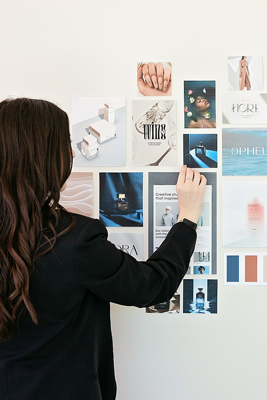 Professional woman adjusting brand board on the wall.
