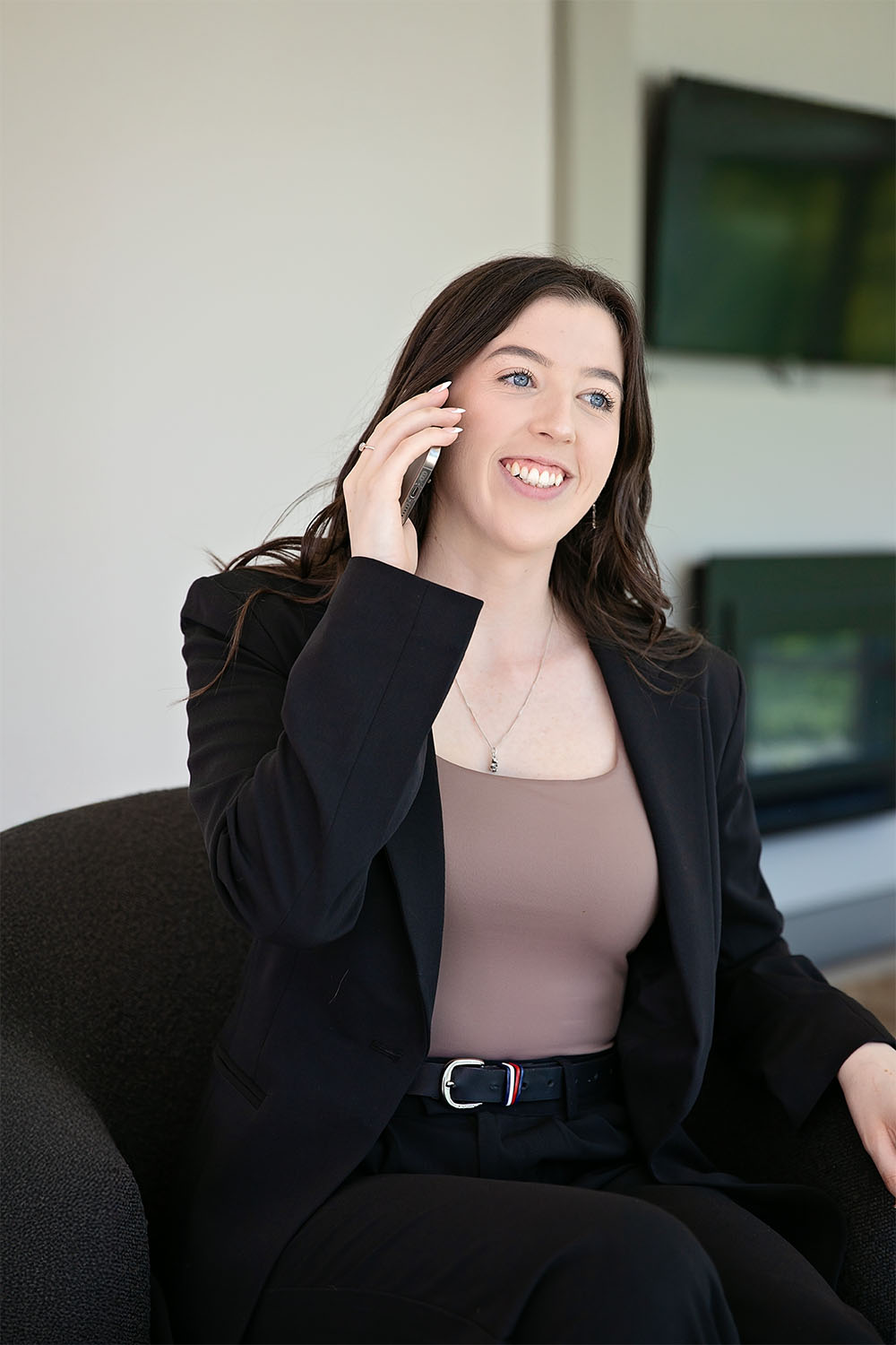 Christchurch New Zealand graphic and web designer Amberley Goulden on a phone to a client wearing a blazer and smiling
