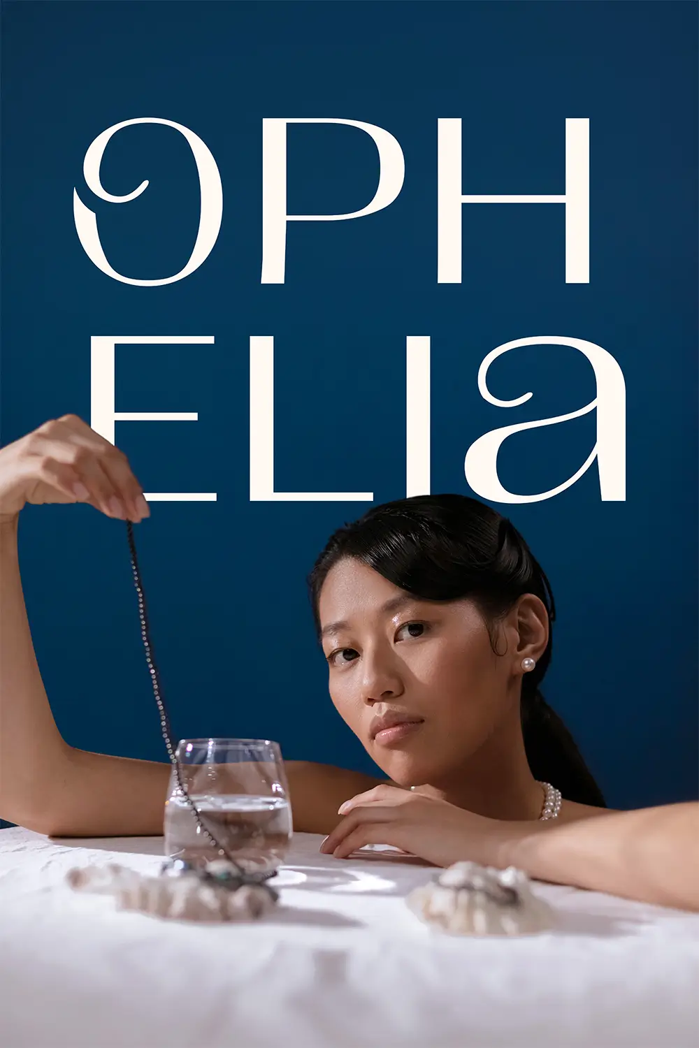 Ophelia brand and website design case study. Ophelia logo behind a luxurious women holding a necklace while leaning on a table top.