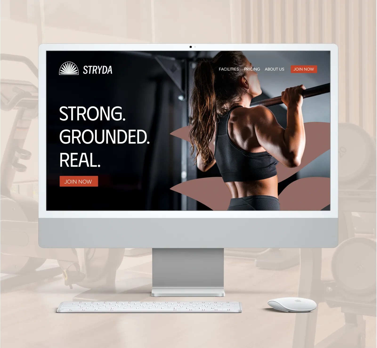 Computer screen displaying STRYDA gym website design with a muscular woman doing pull-ups with a brand asset behind her, and text saying 'STRONG. GROUNDED. REAL.'
