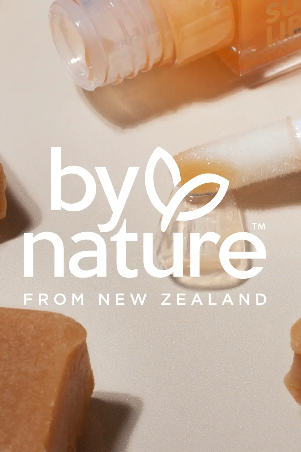 By Nature From New Zealand logo overlaying an image of a Caramel Sundae Lip Oil swatching on a light background surrounded by caramel fudge