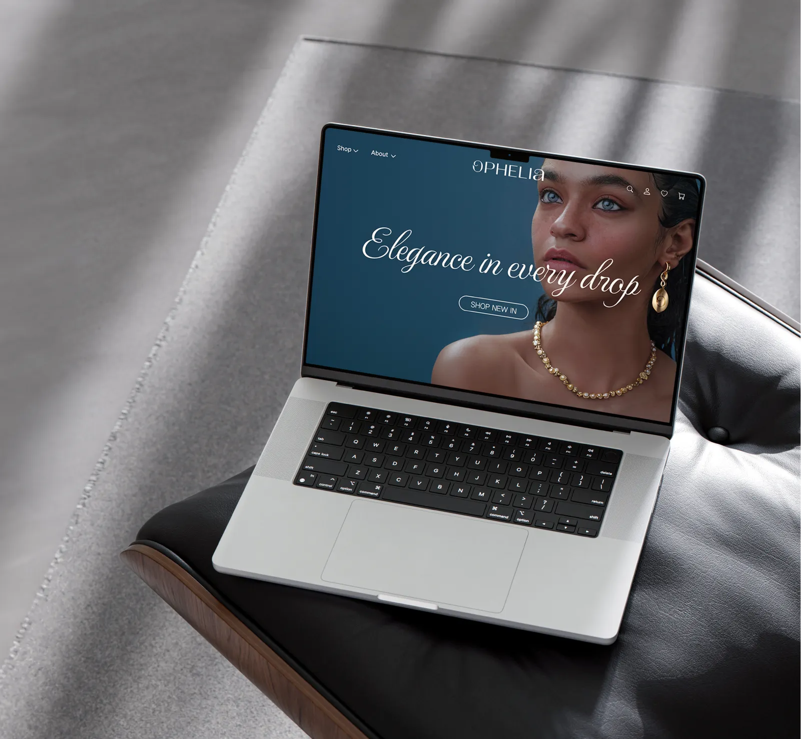 Professional website design for an editorial jewellery brand, shown on a laptop mockup resting on a leather chair, featuring the tagline 'Elegance in every drop.'